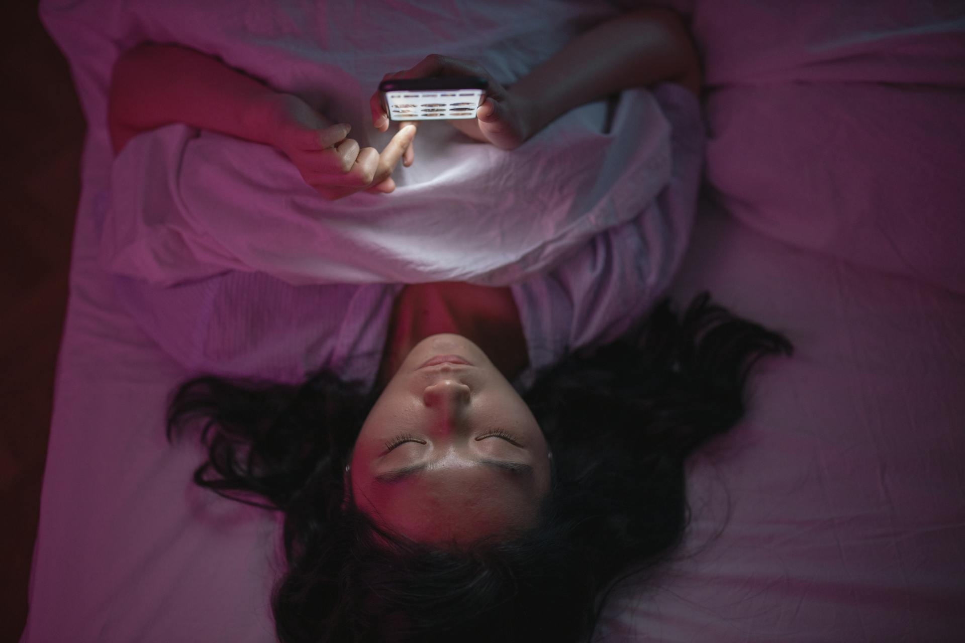 Une femme qui regarde son téléphone au lit | Source : Pexels