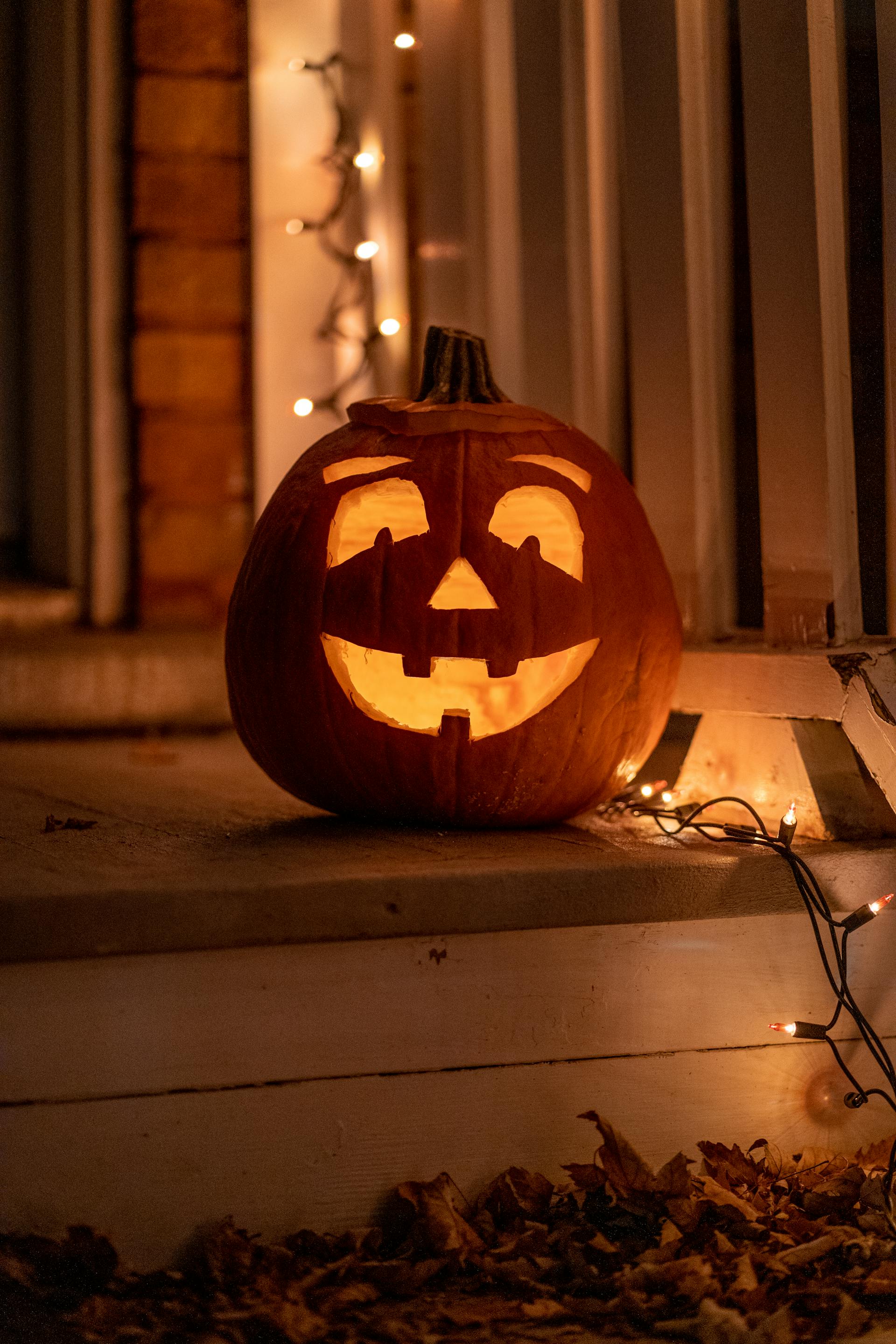Une citrouille sculptée pour Halloween posée à côté de lumières scintillantes | Source : Pexels