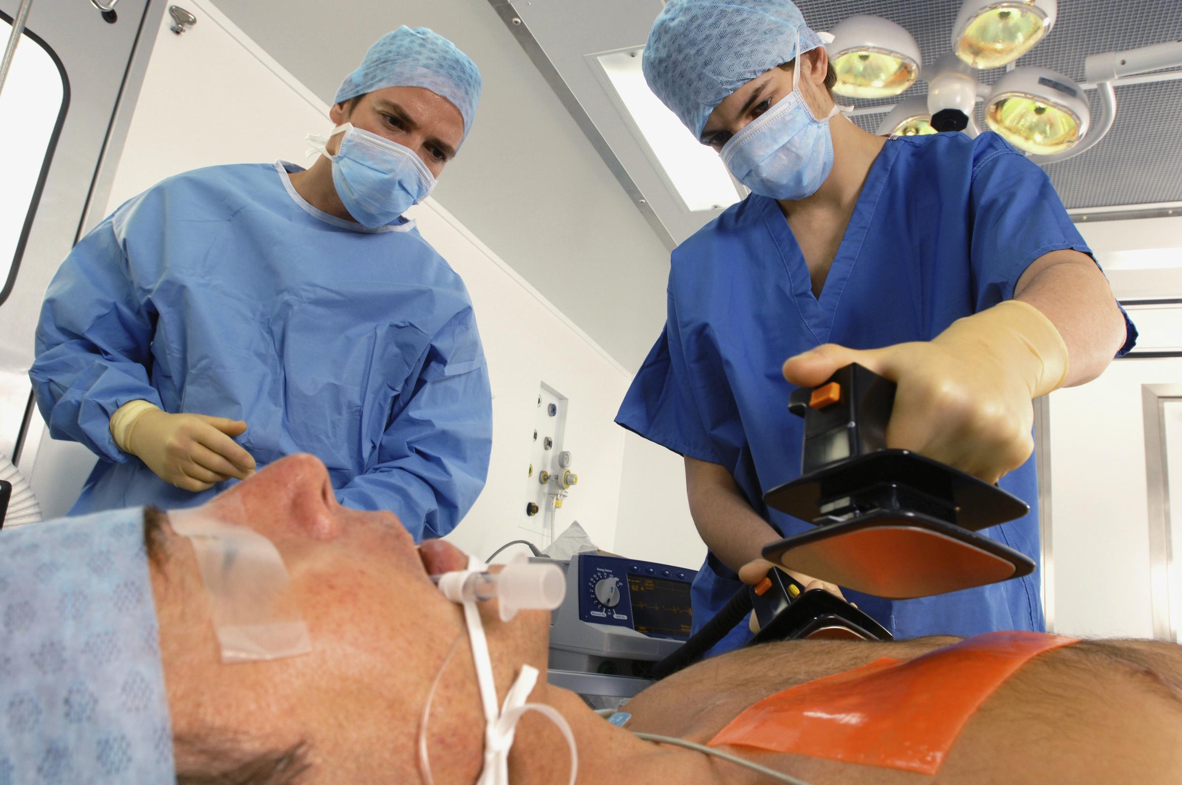 Des médecins qui utilisent un défibrillateur pour réanimer un homme victime d'une crise cardiaque | Source : Getty Images