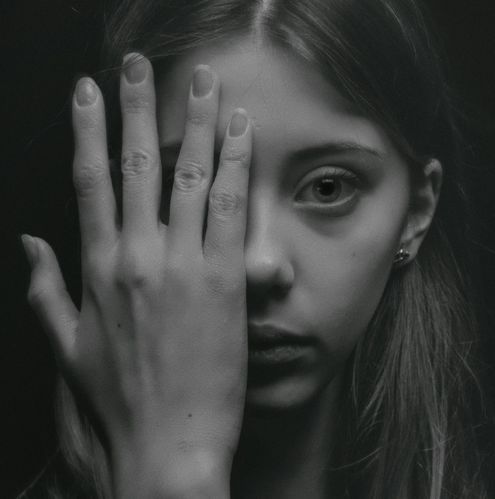 Une photo en niveaux de gris d'une jeune femme couvrant la moitié de son visage | Source : Pexels