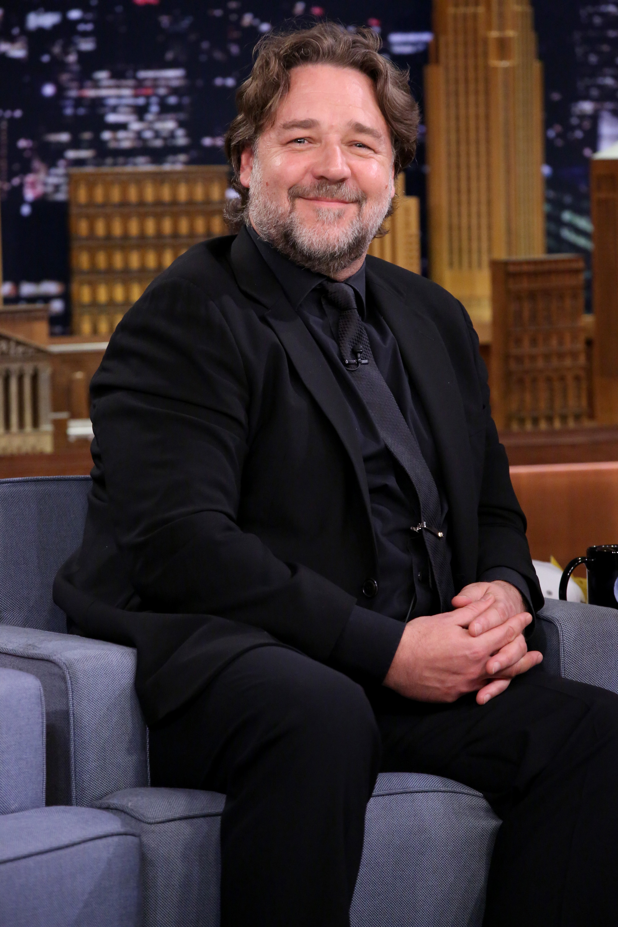 Russell Crowe participe à une interview dans l'émission « The Tonight Show Starring Jimmy Fallon » le 22 avril 2015, vêtu d'un costume noir et d'une cravate assortie. À cette époque, l'acteur semblait nettement plus corpulent, plusieurs années avant d'entamer un parcours axé sur la santé qui lui permettra de perdre 25 kg.