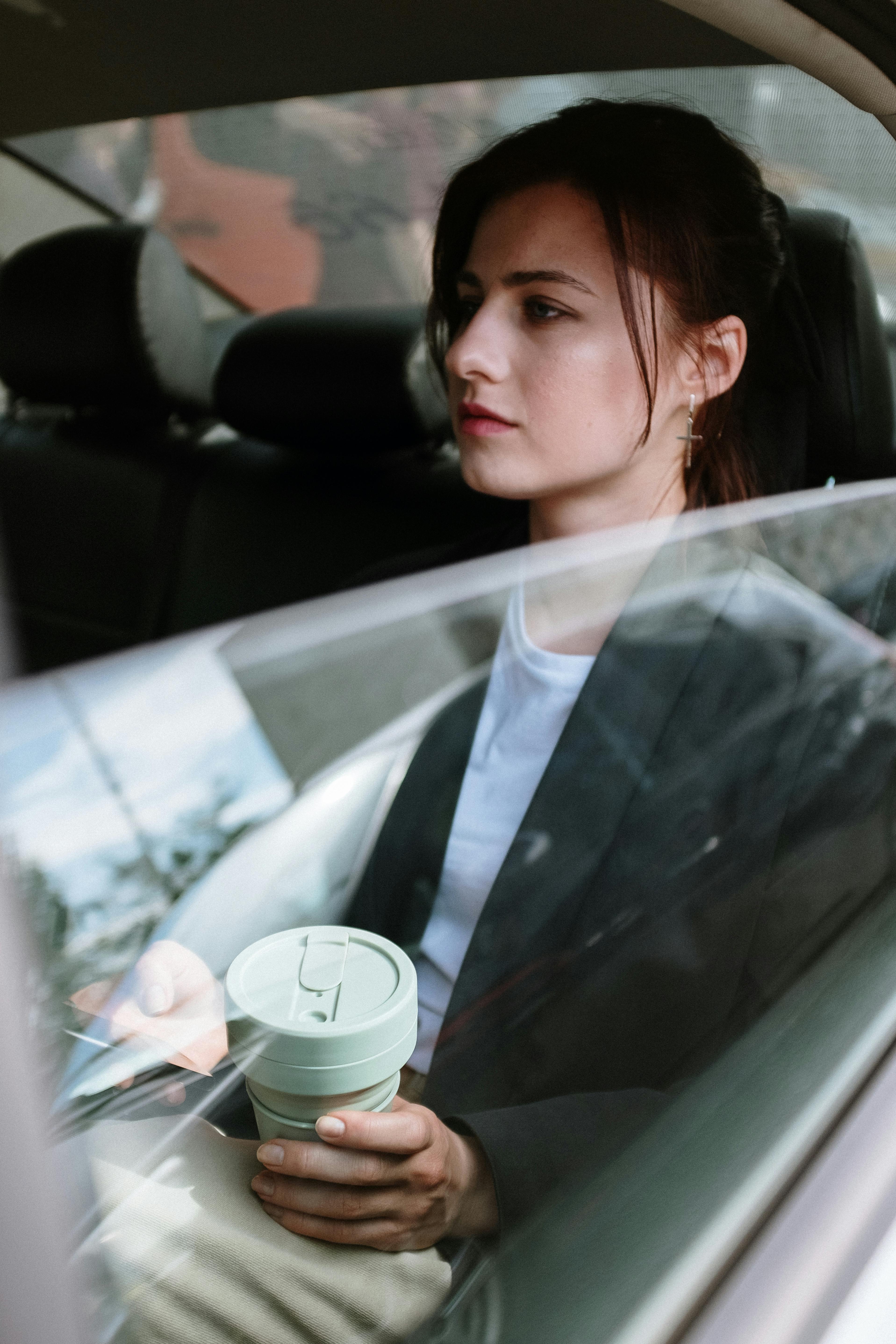Une femme sérieuse sur la banquette arrière d'une voiture | Source : Pexels