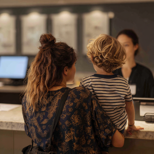 Une femme et un enfant s'adressant à une réceptionniste | Source : Midjourney
