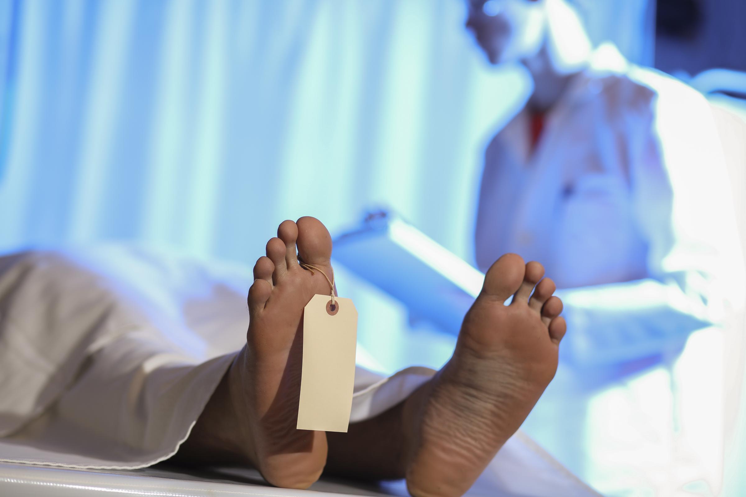 Un médecin légiste examine le corps d'un homme mort à la morgue. Il prend des notes sur le dossier médical après l'autopsie — Photo d’illustration I Source : Getty Images
