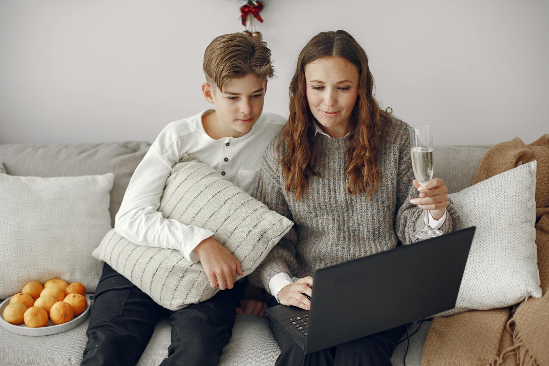 Un duo mère-fils assis sur un canapé et utilisant un ordinateur portable | Source : Pexels
