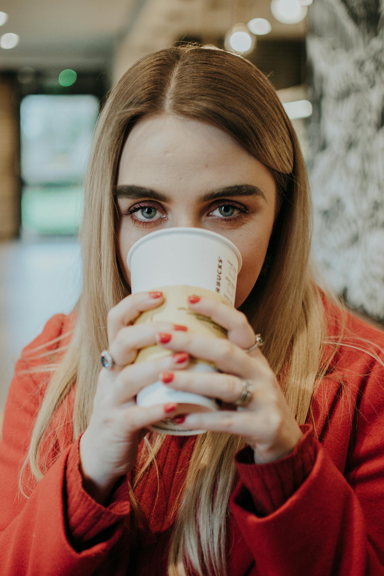 Une femme qui boit dans un gobelet jetable en regardant curieusement | Source : Pexels