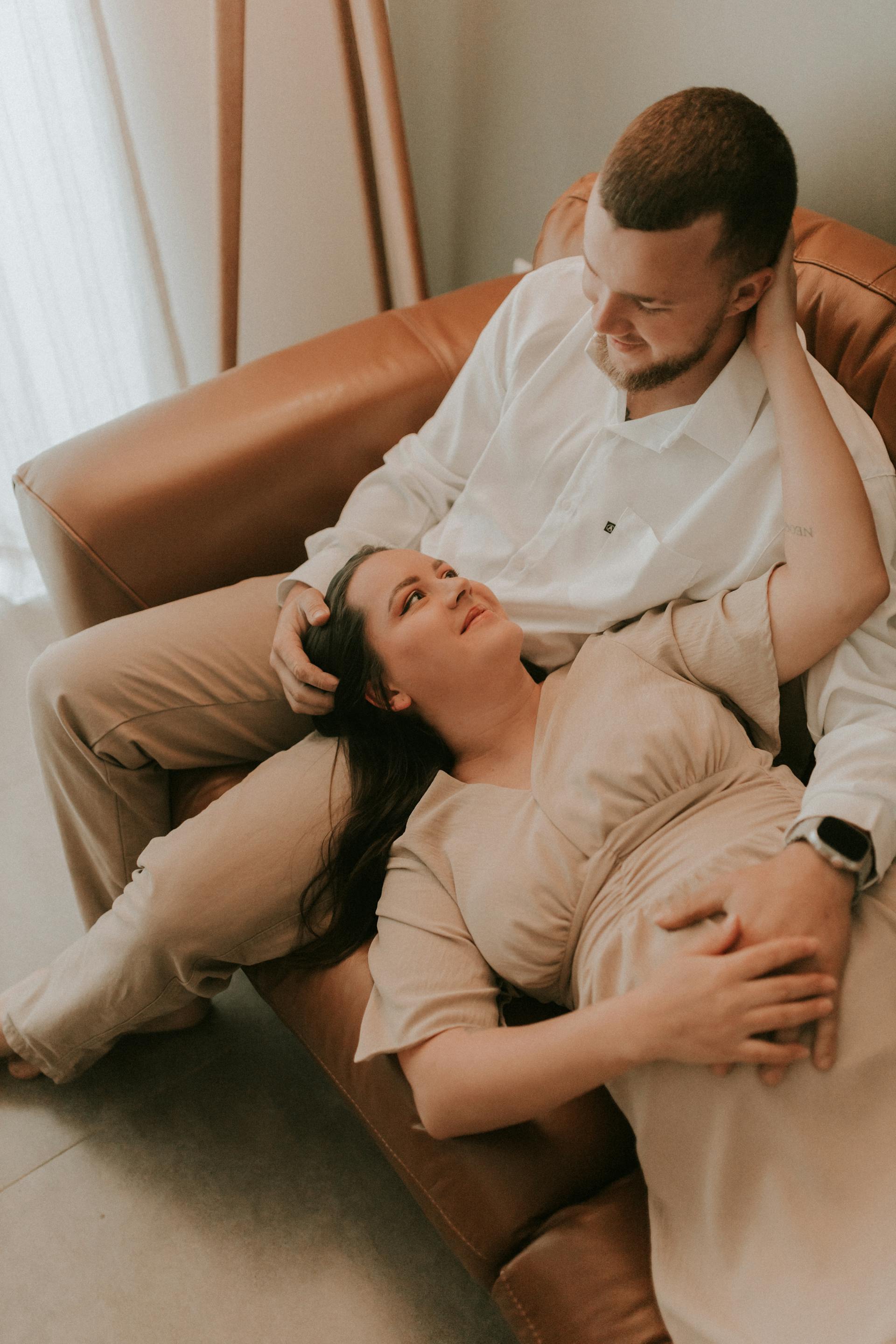 Une femme enceinte allongée sur les genoux de son mari sur un canapé | Source : Pexels