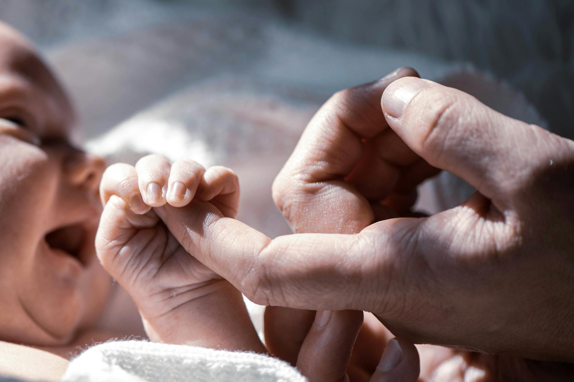 Un bébé tenant le doigt d'un homme | Source : Pexels