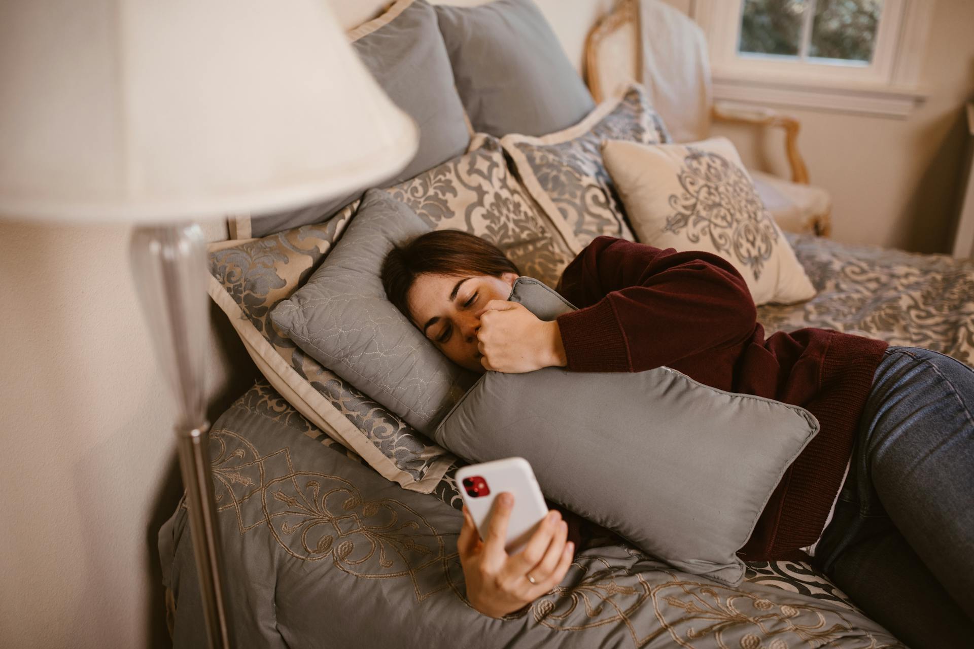 Une femme consulte son smartphone alors qu'elle est allongée dans son lit | Source : Pexels