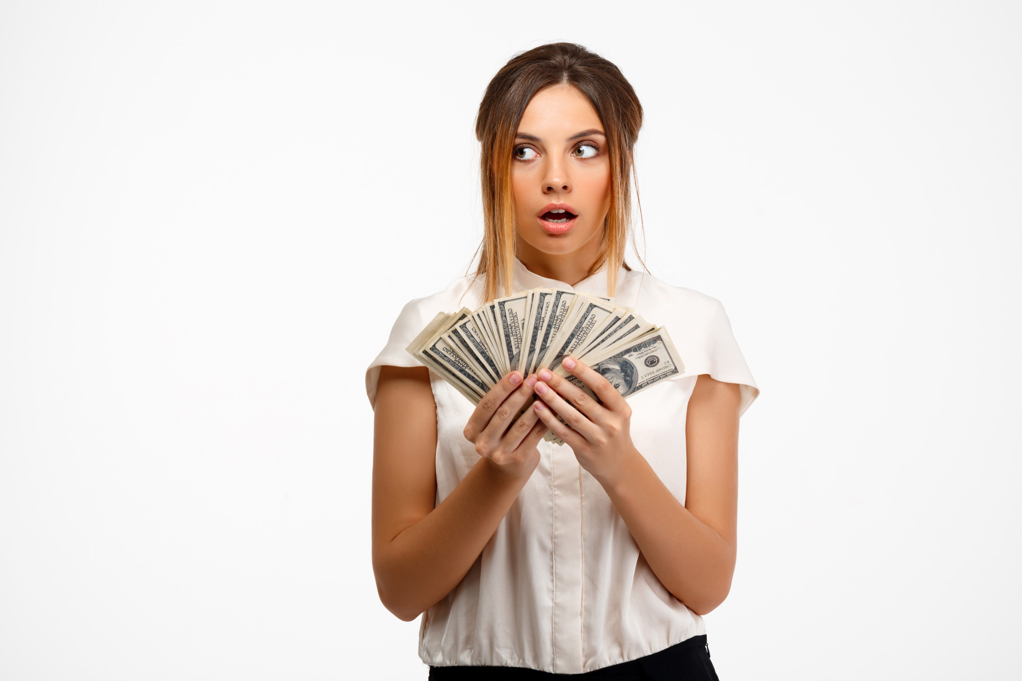 Une jeune femme avec un air surpris alors qu'elle tient de l'argent | Source : Freepik