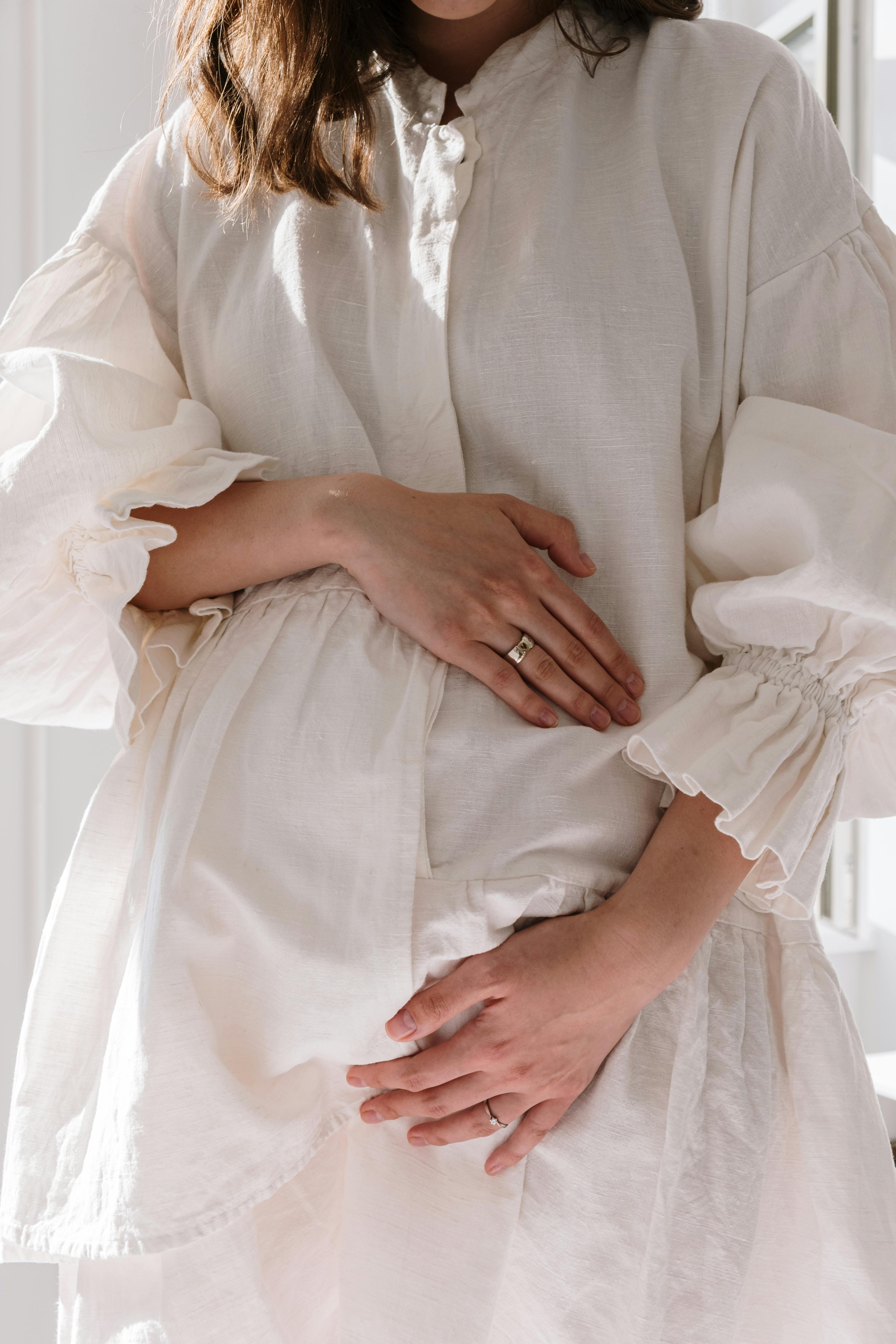 Une femme en robe blanche se tenant le ventre | Source : Pexels