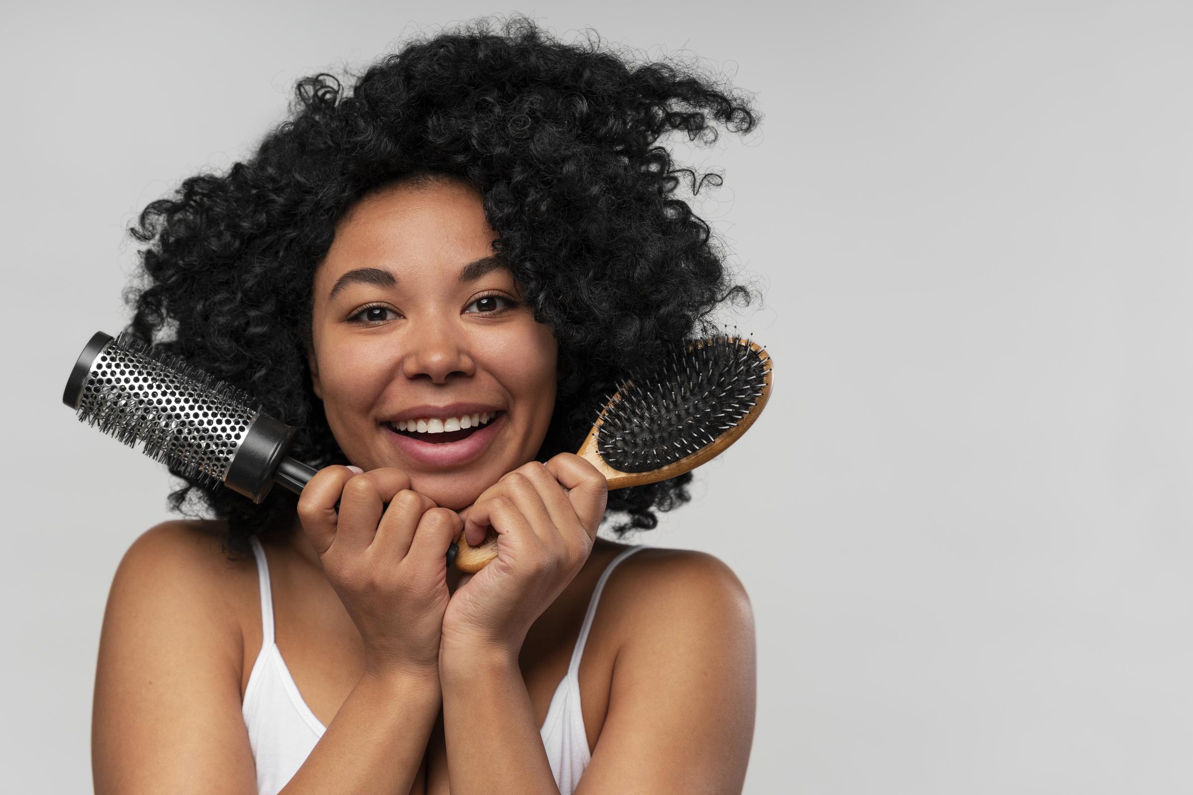 Une femme heureuse avec des brosses à cheveux | Source : Freepik