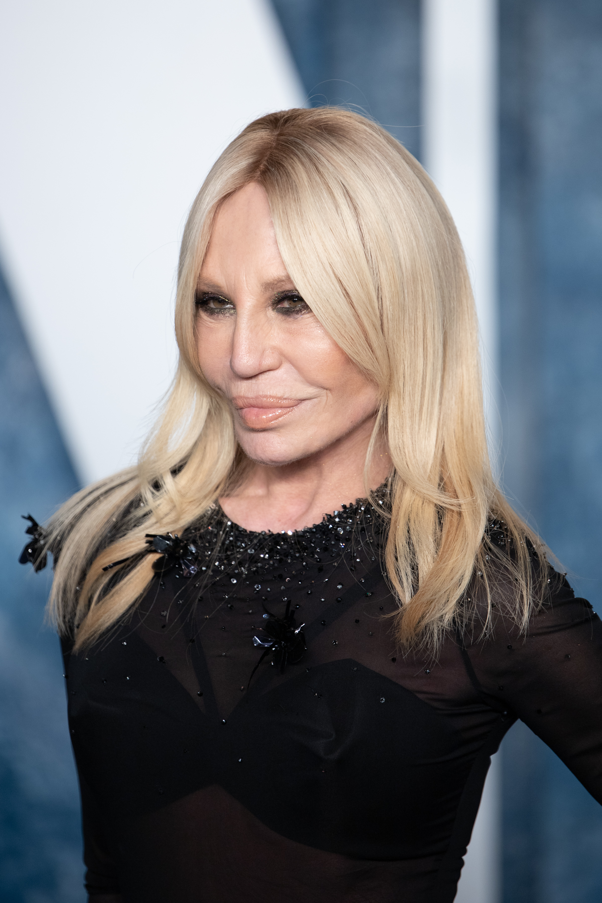 Donatella Versace, 67 ans, à la soirée Vanity Fair Oscar Party le 12 mars 2023 à Beverly Hills, en Californie. Son visage présentait des rides profondes le long des joues et de la mâchoire, un fard à paupières foncé très prononcé et une courbe tendue vers le haut au niveau de ses lèvres volumineuses et brillantes.