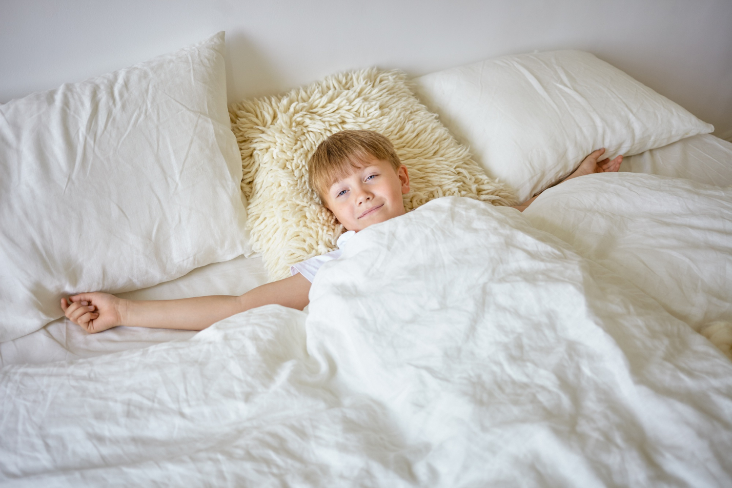 Un garçon joyeux qui sourit depuis son lit | Source : Freepik