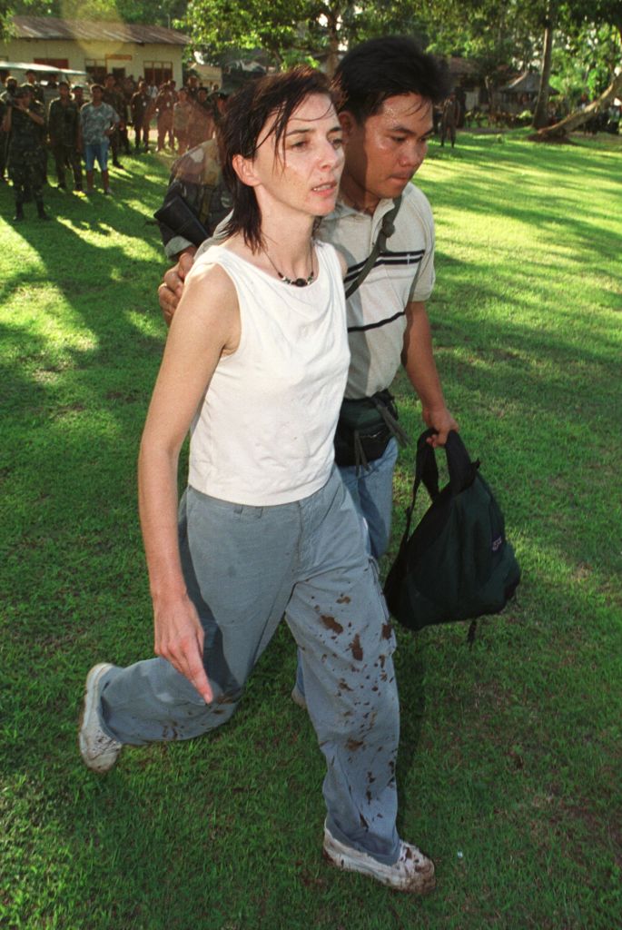 L'otage française Maryse Burgot, journaliste, marche aux côtés d'un garde présidentiel philippin après sa libération le 27 août 2000 par des séparatistes musulmans aux Philippines. (Photo by Pool/Liaison)