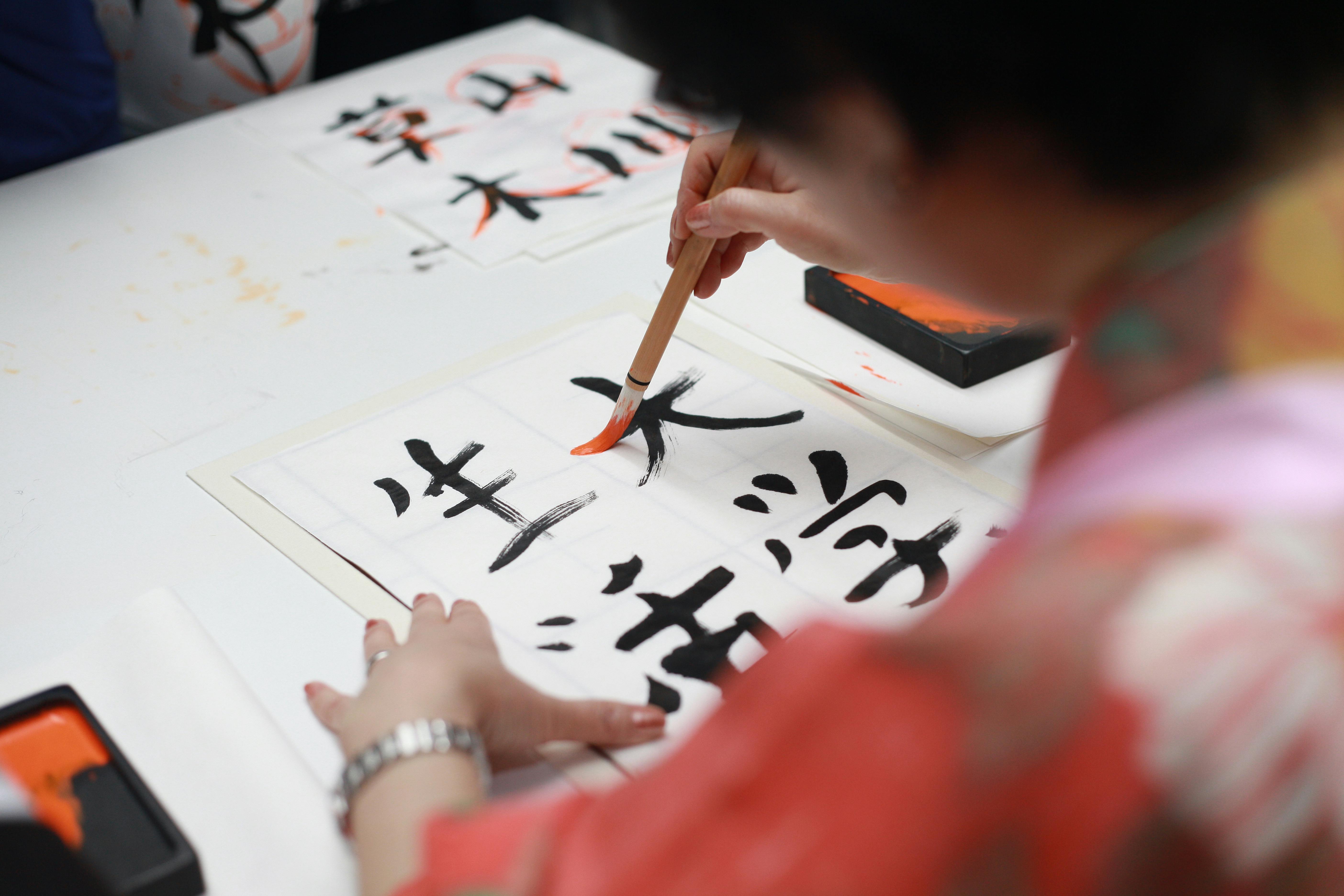 Une personne tenant un pinceau et dessinant l'écriture Kanji | Source : Pexels
