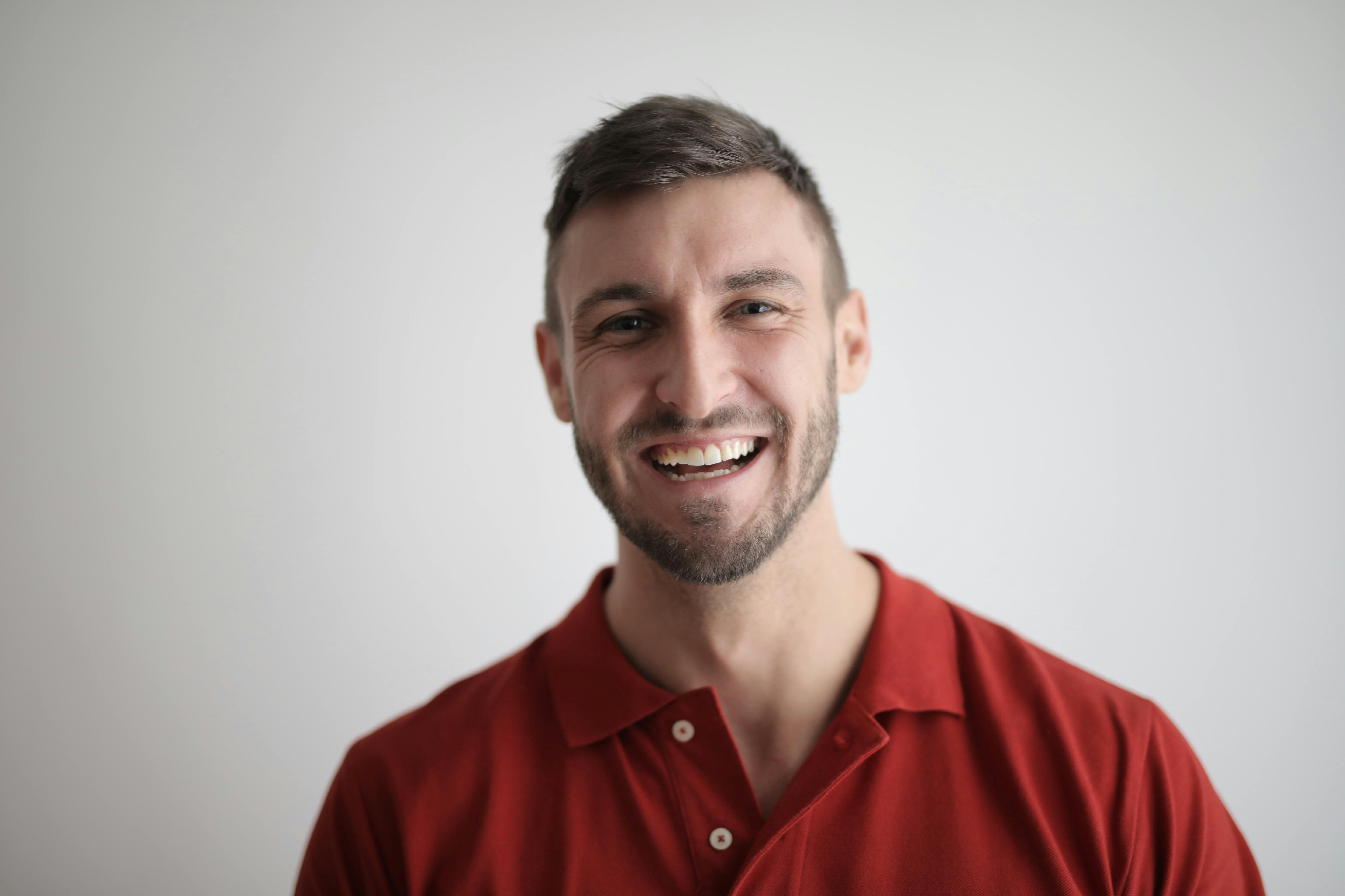 Un homme rieur portant un golfeur rouge | Source : Pexels