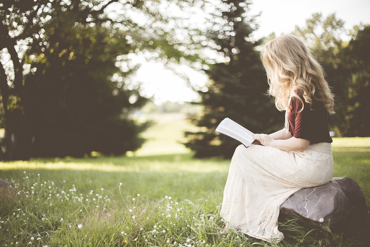 Une femme lisant un livre à l'extérieur | Source : Pixabay