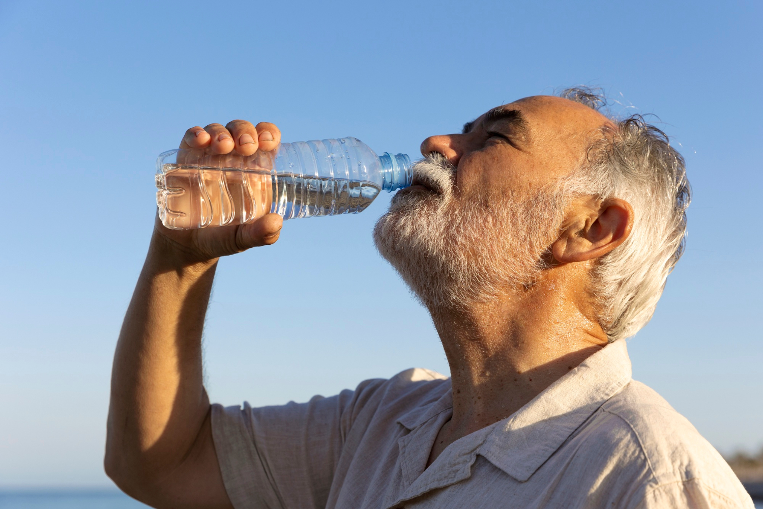 Un homme âgé qui boit une bouteille d'eau | Source : Freepik