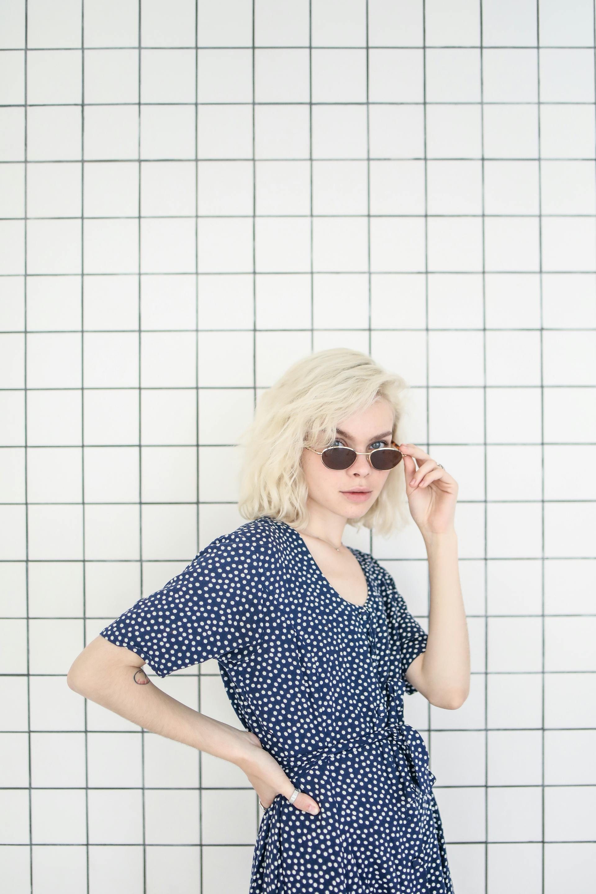 Une jeune femme qui regarde par-dessus le haut de ses lunettes de soleil | Source : Pexels