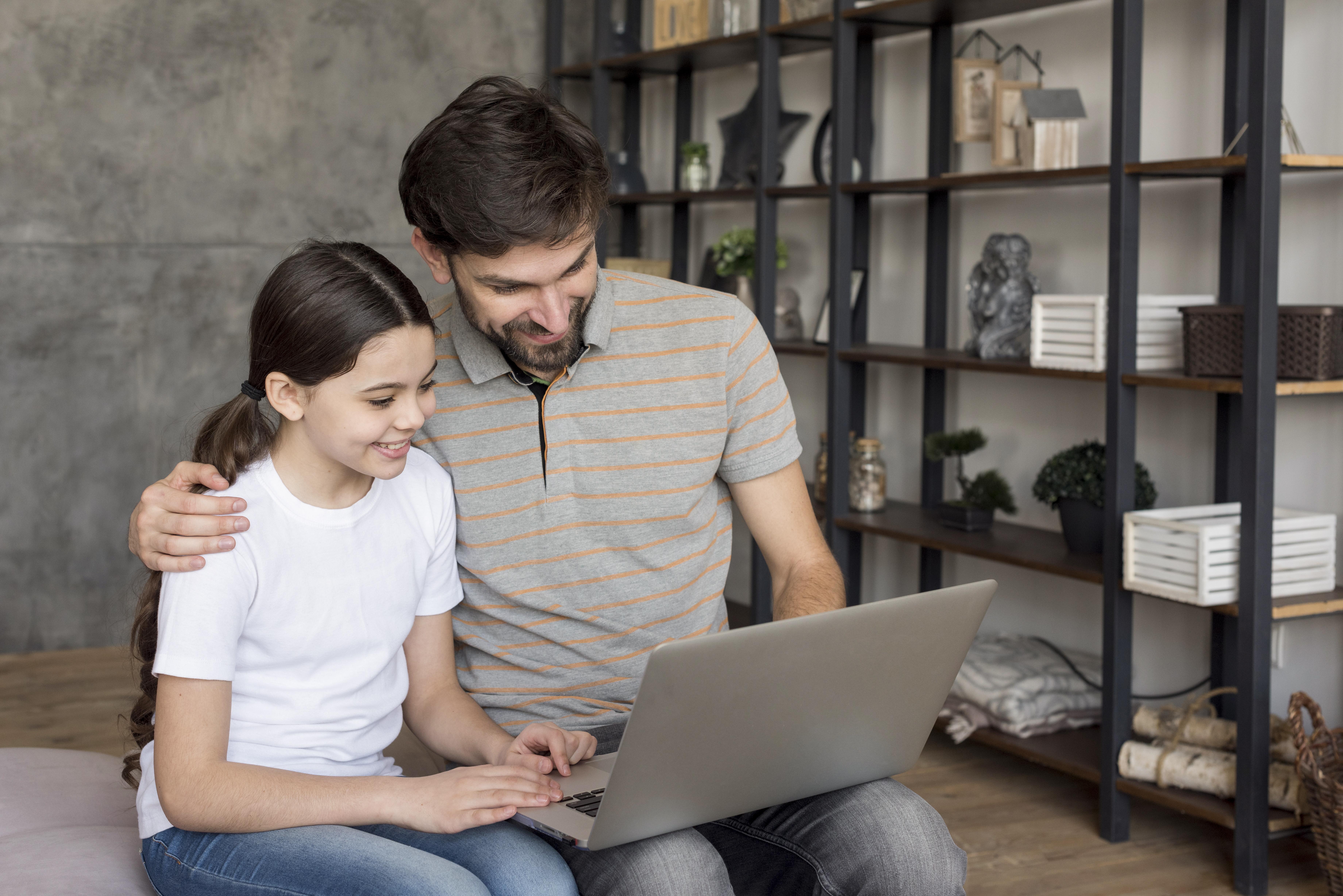 Une fille et son père utilisant un ordinateur portable | Source : Freepik