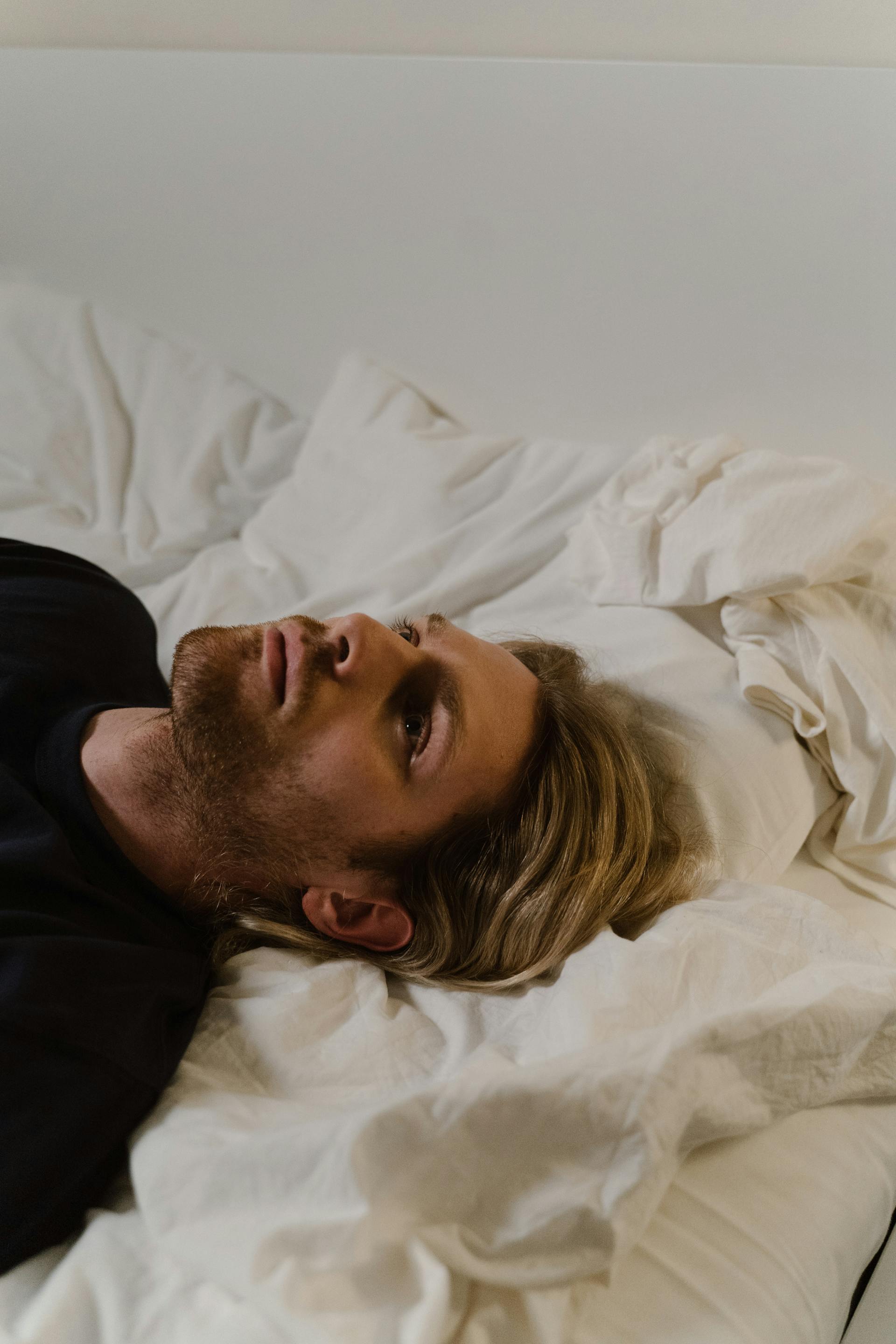 Un homme allongé sur le lit avec les yeux ouverts | Source : Pexels