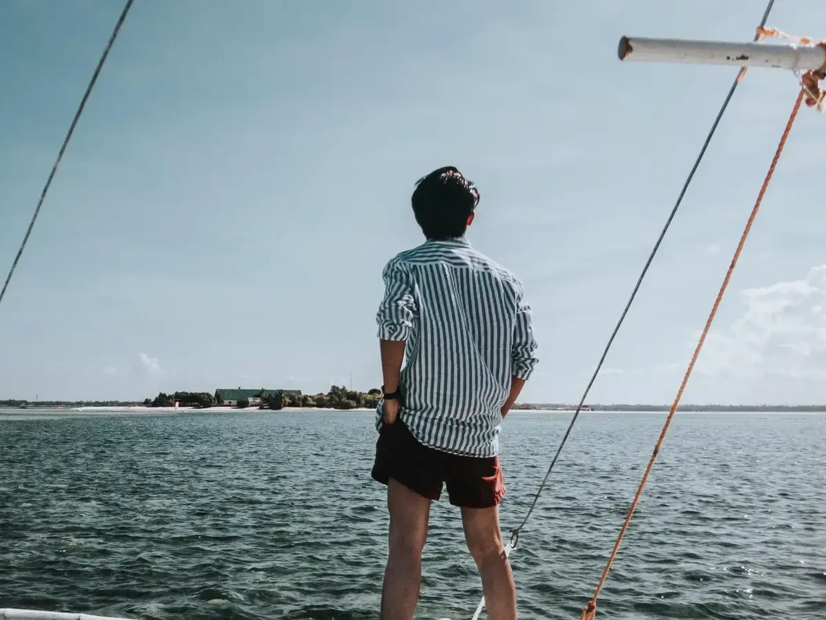Un homme regarde par-dessus bord en direction d'une petite île au large | Source : Pexels