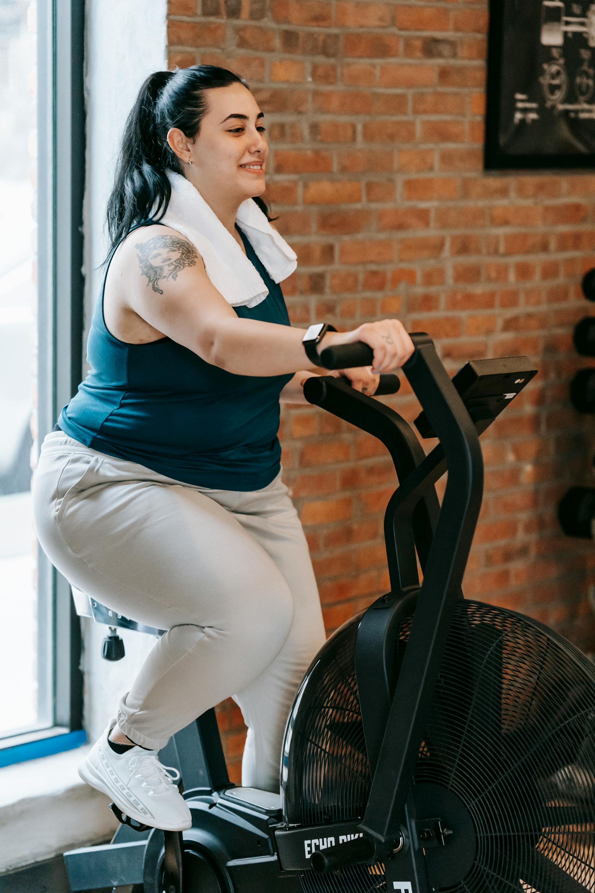 Une femme de grande taille sur un appareil de cross trainer dans une salle de sport | Source : Pexels