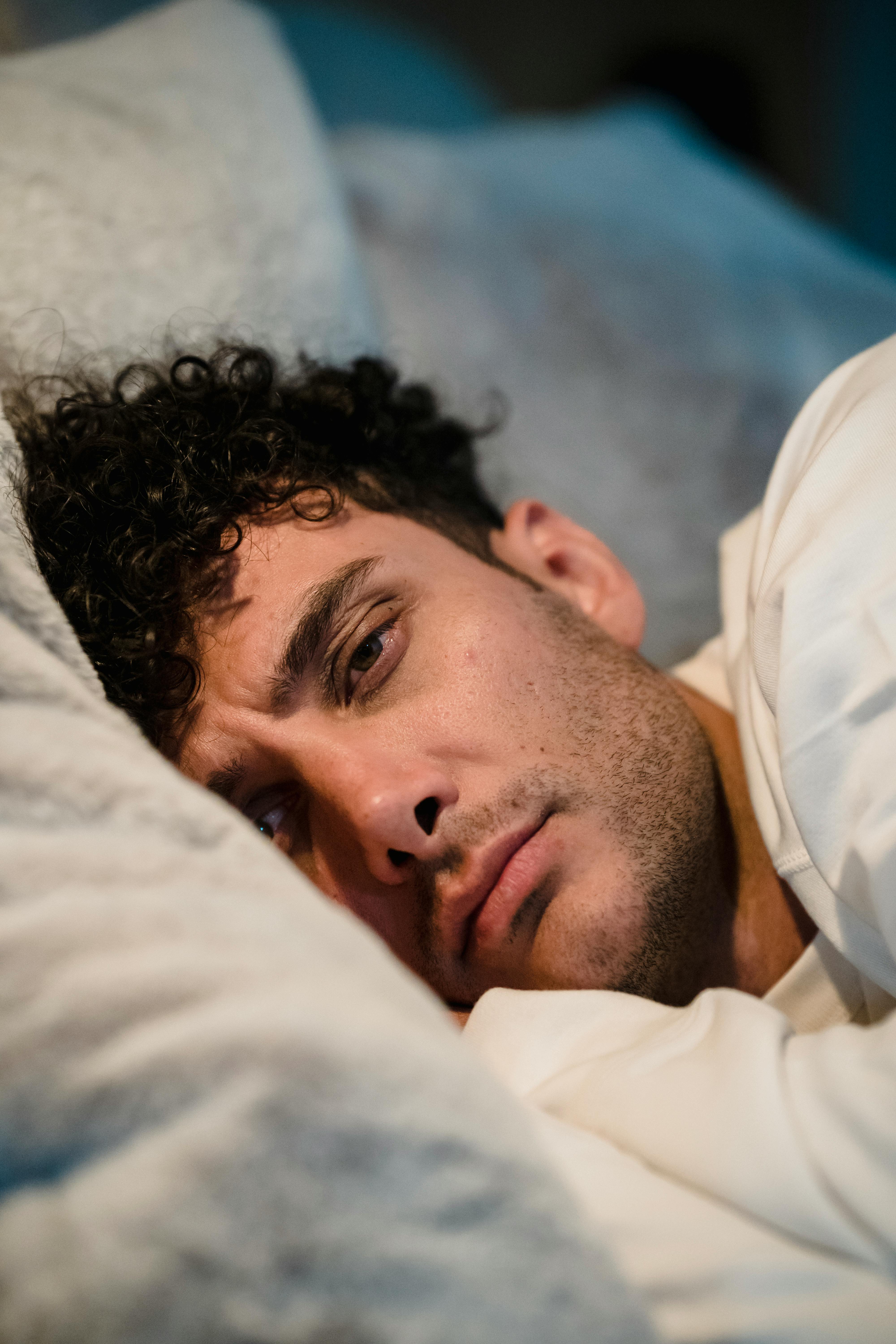 Un homme qui fronce les sourcils, allongé dans son lit | Source : Midjourney