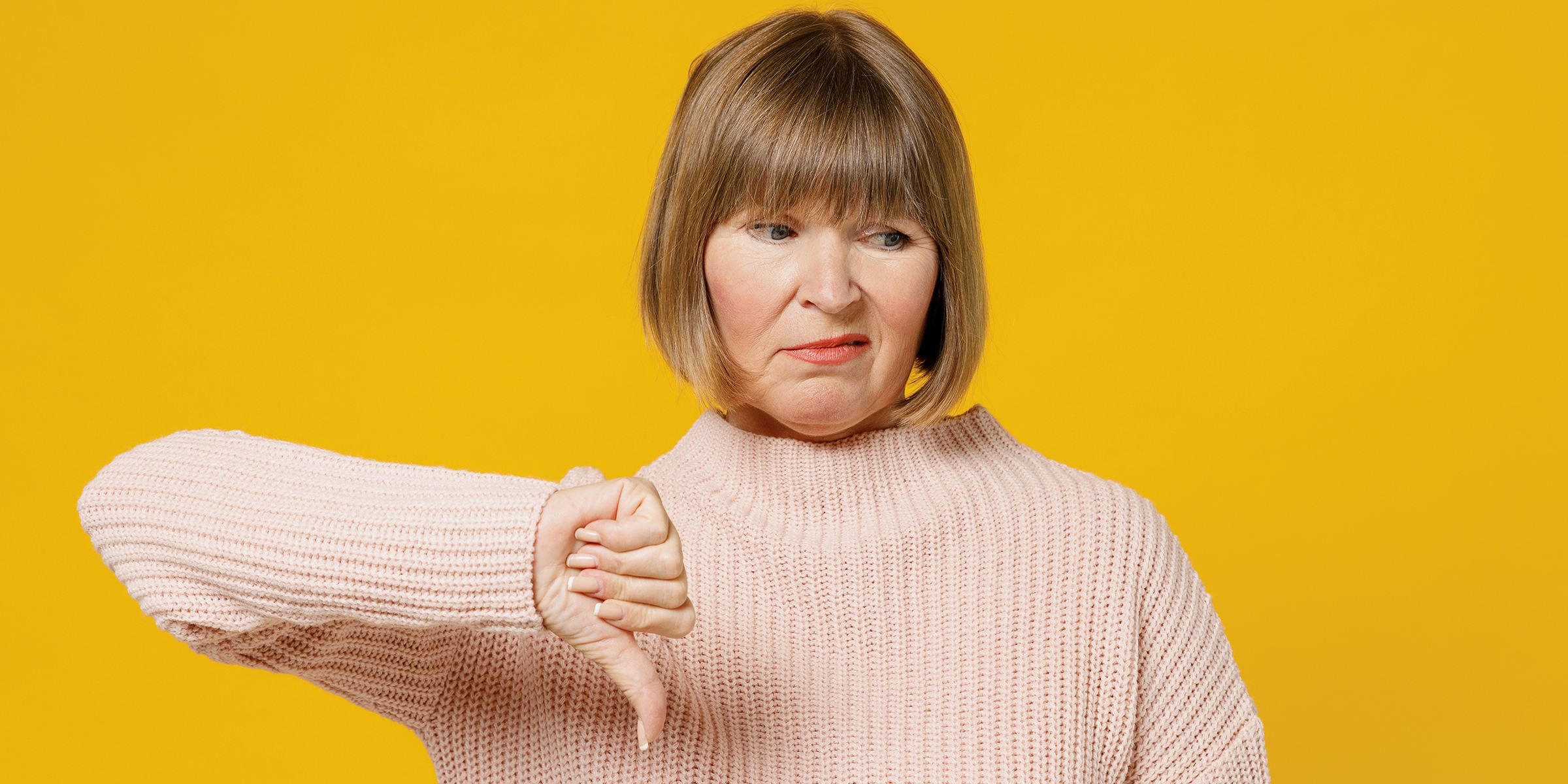 Une femme malheureuse faisant le signe du pouce vers le bas | Source : Shutterstock