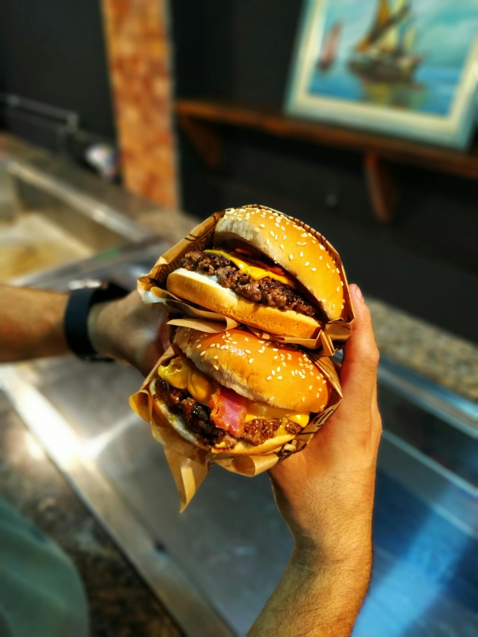 Gros plan d'un homme tenant deux hamburgers | Source : Pexels