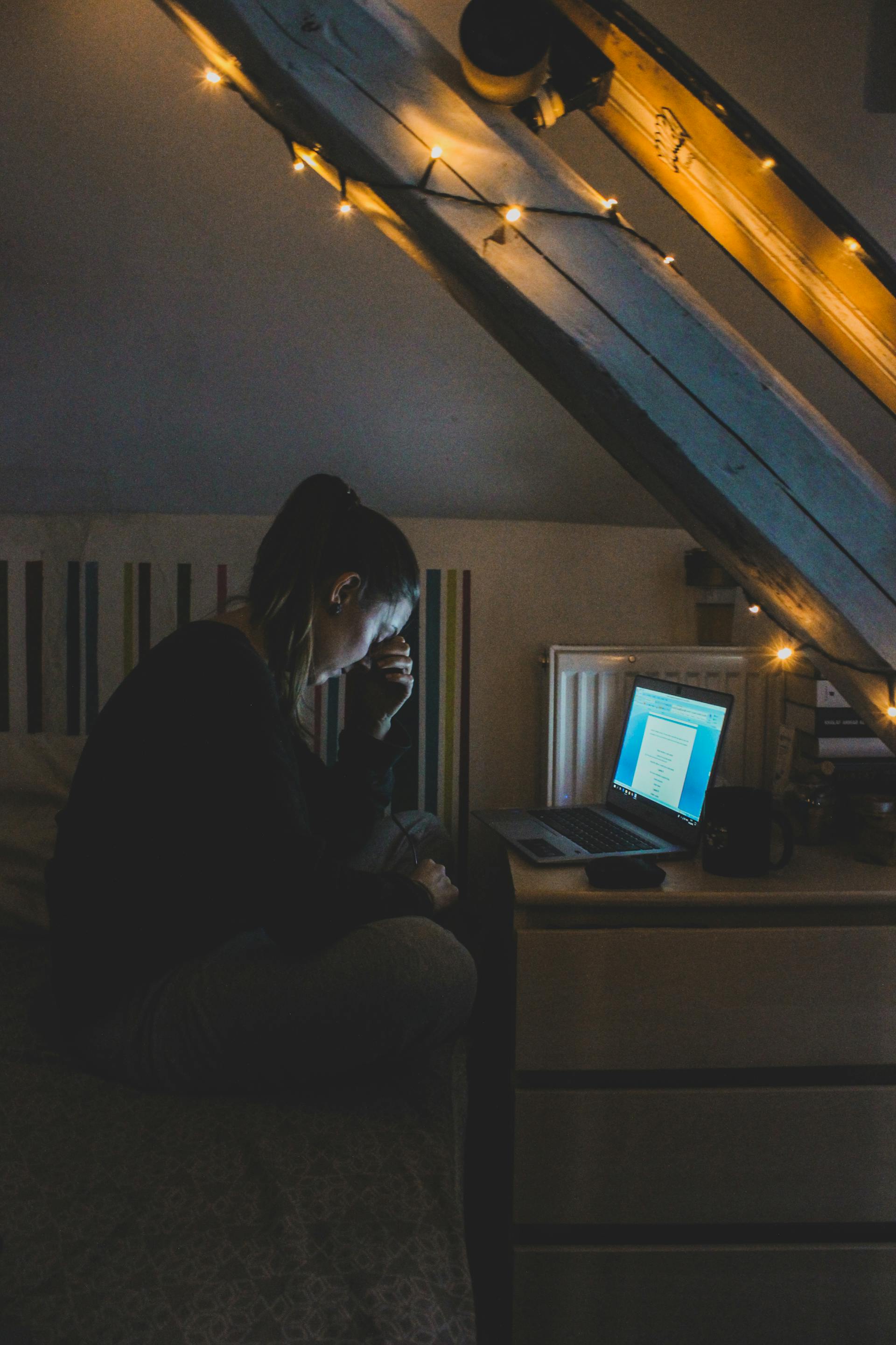 Une femme qui semble être désemparée alors qu'elle utilise son ordinateur portable la nuit | Source : Pexels