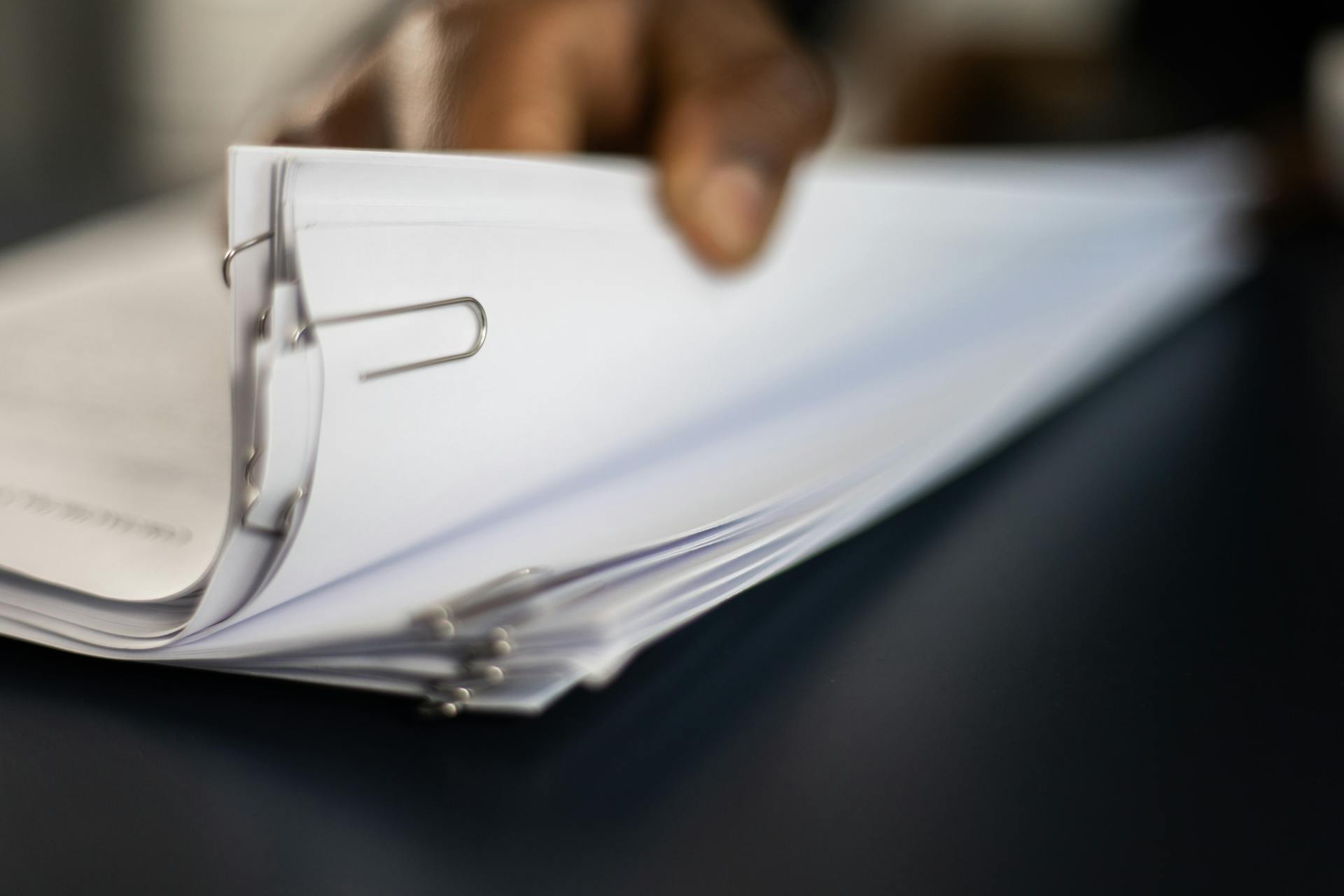 Une personne tenant une pile de documents épinglés | Source : Pexels