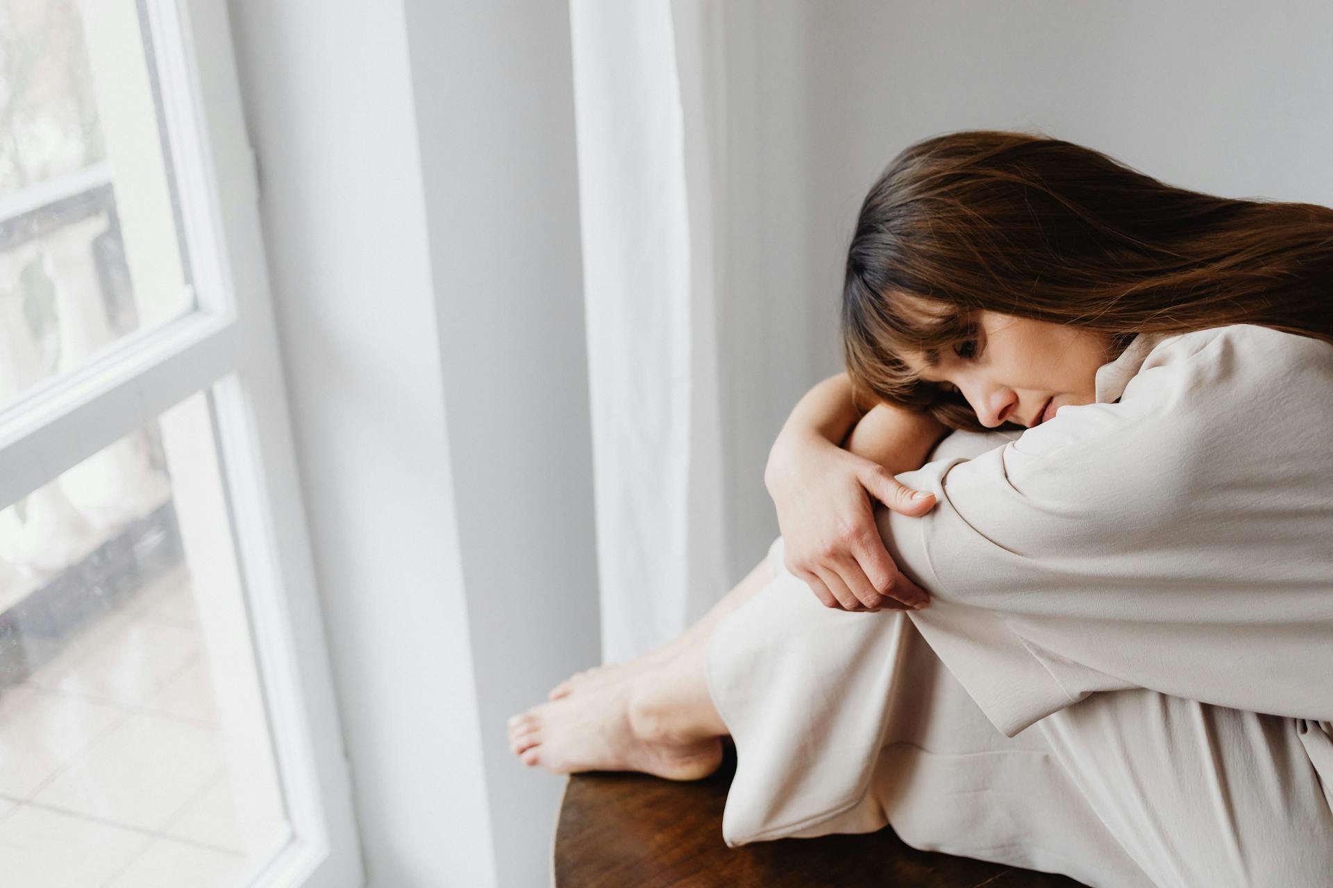 Une femme en détresse assise près de la fenêtre | Source : Pexels