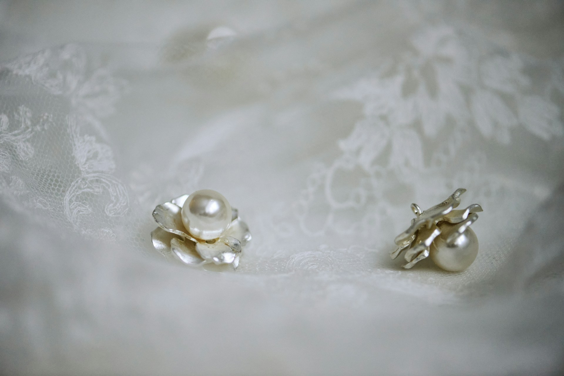 Une paire de boucles d'oreilles en perles sur un tissu en dentelle | Source : Unsplash