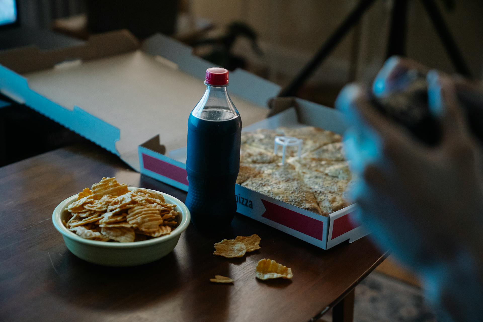Une personne dégustant une pizza, un cola et des chips | Source : Pexels