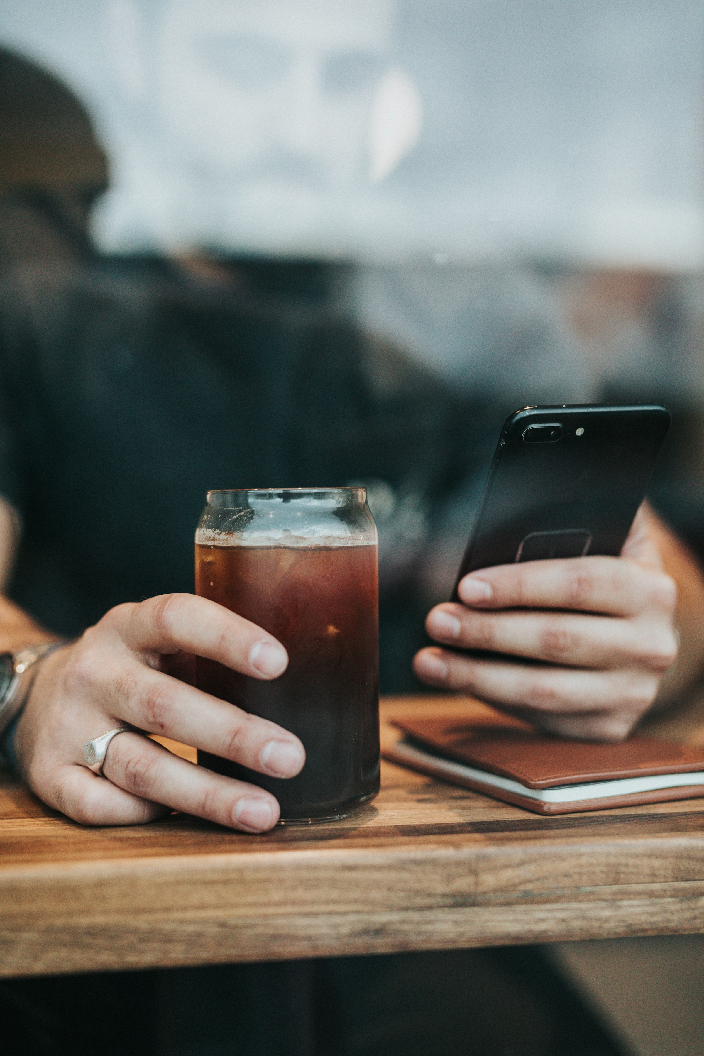 Un homme utilisant son téléphone tout en tenant un verre | Source : Unsplash