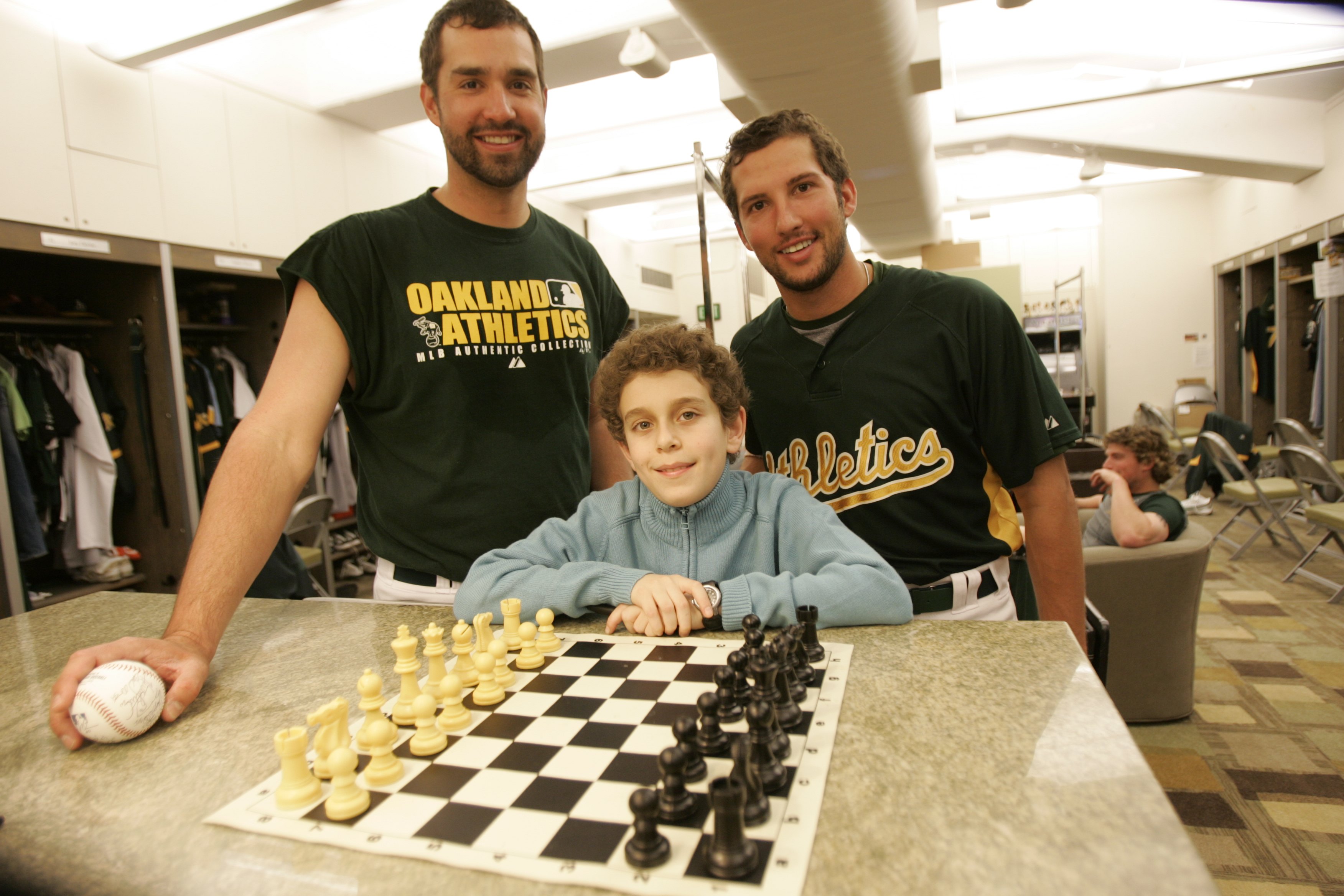 Le champion d'échecs Daniel Naroditsky rencontre Andrew Brown et Huston Street des Oakland Athletics dans le clubhouse avant le match contre les Minnesota Twins au McAfee Coliseum à Oakland, Californie, le 23 avril 2008. | Source : Getty Images