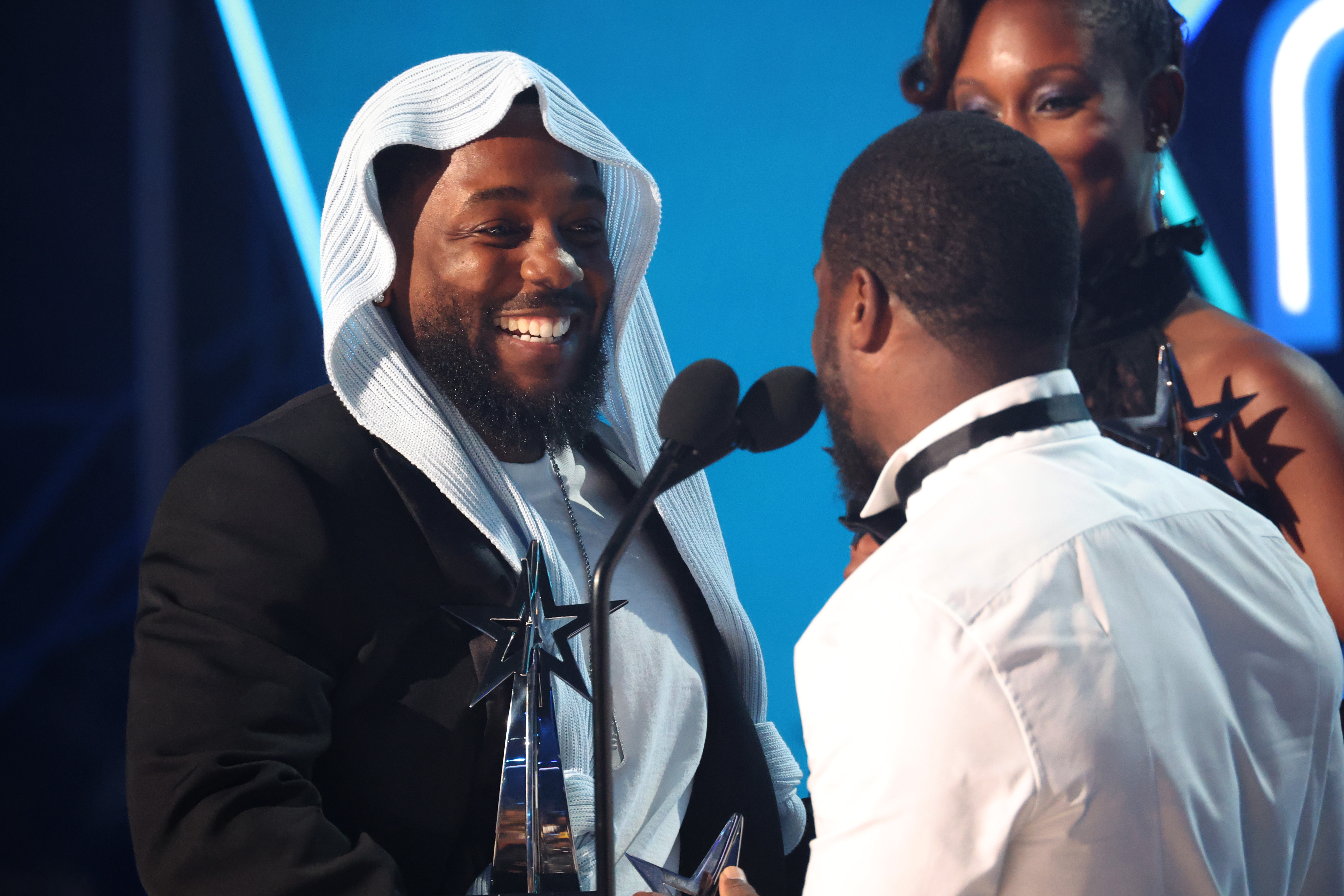 Kendrick Lamar rit avec Kevin Hart lors d'un moment de légèreté sur la scène des BET Awards 2025. Entourés d'autres artistes, la camaraderie du duo et l'impressionnante pile de récompenses de Lamar ont apporté de la légèreté aux triomphes de la nuit.