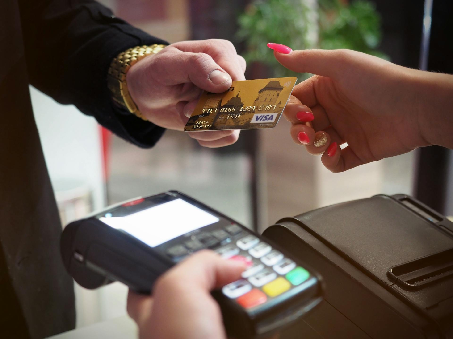Un homme tend sa carte à une caissière pour qu'elle la glisse en vue d'un paiement | Source : Pexels