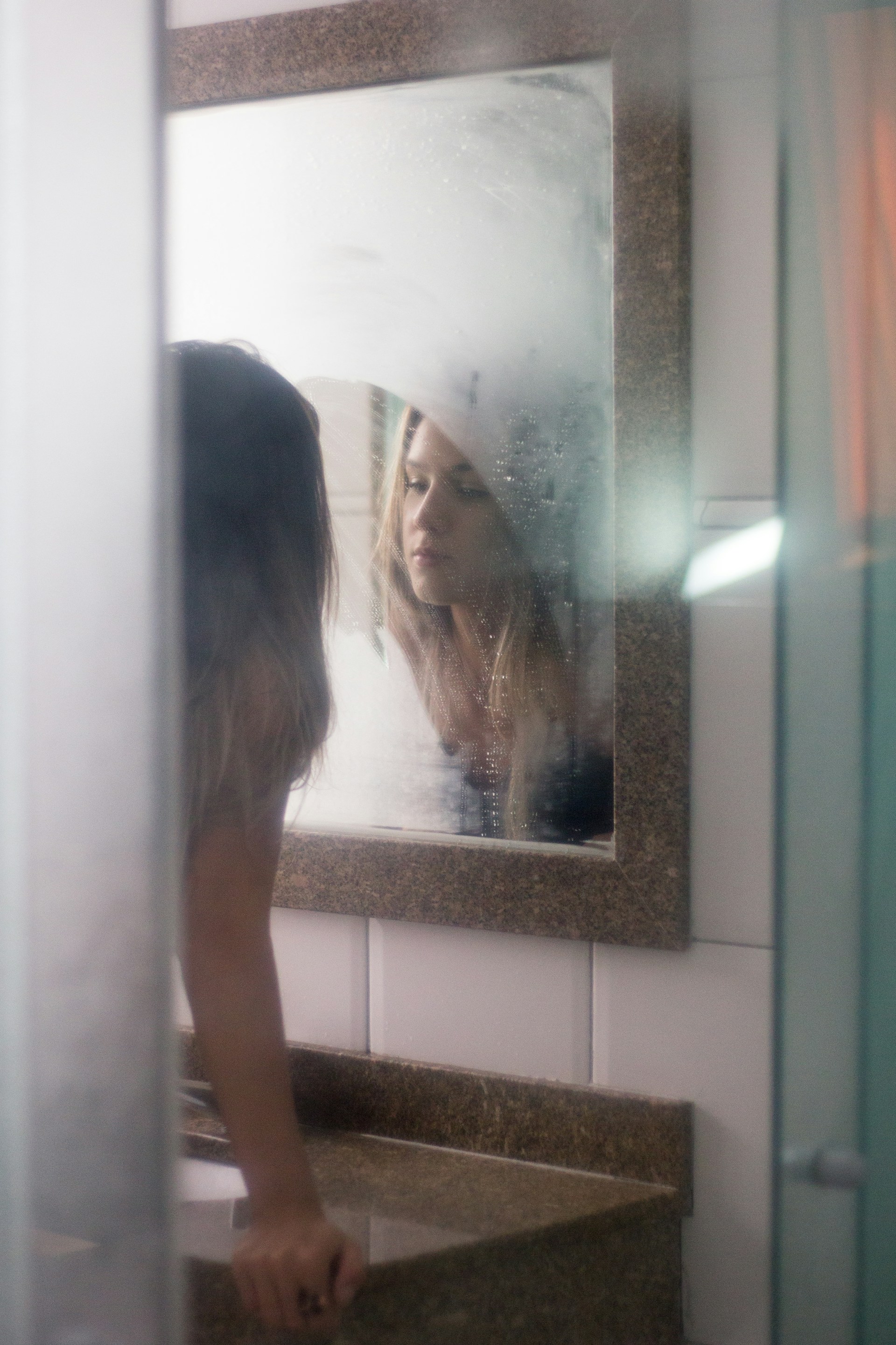 Une femme se regardant dans le miroir d'une salle de bain | Source : Unsplash