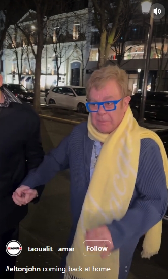 Portant des lunettes bleu vif et une écharpe jaune, Sir Elton John semble tendu alors qu'il passe devant les caméras. | Source : Instagram/taoualit__amar