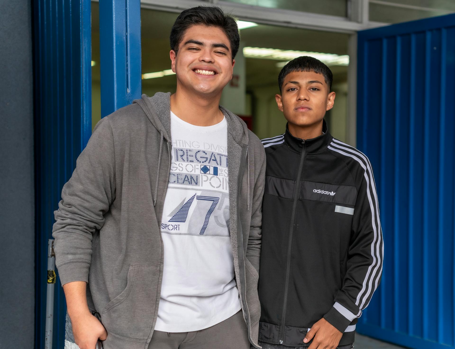 Deux jeunes hommes debout devant une porte bleue | Source : Pexels