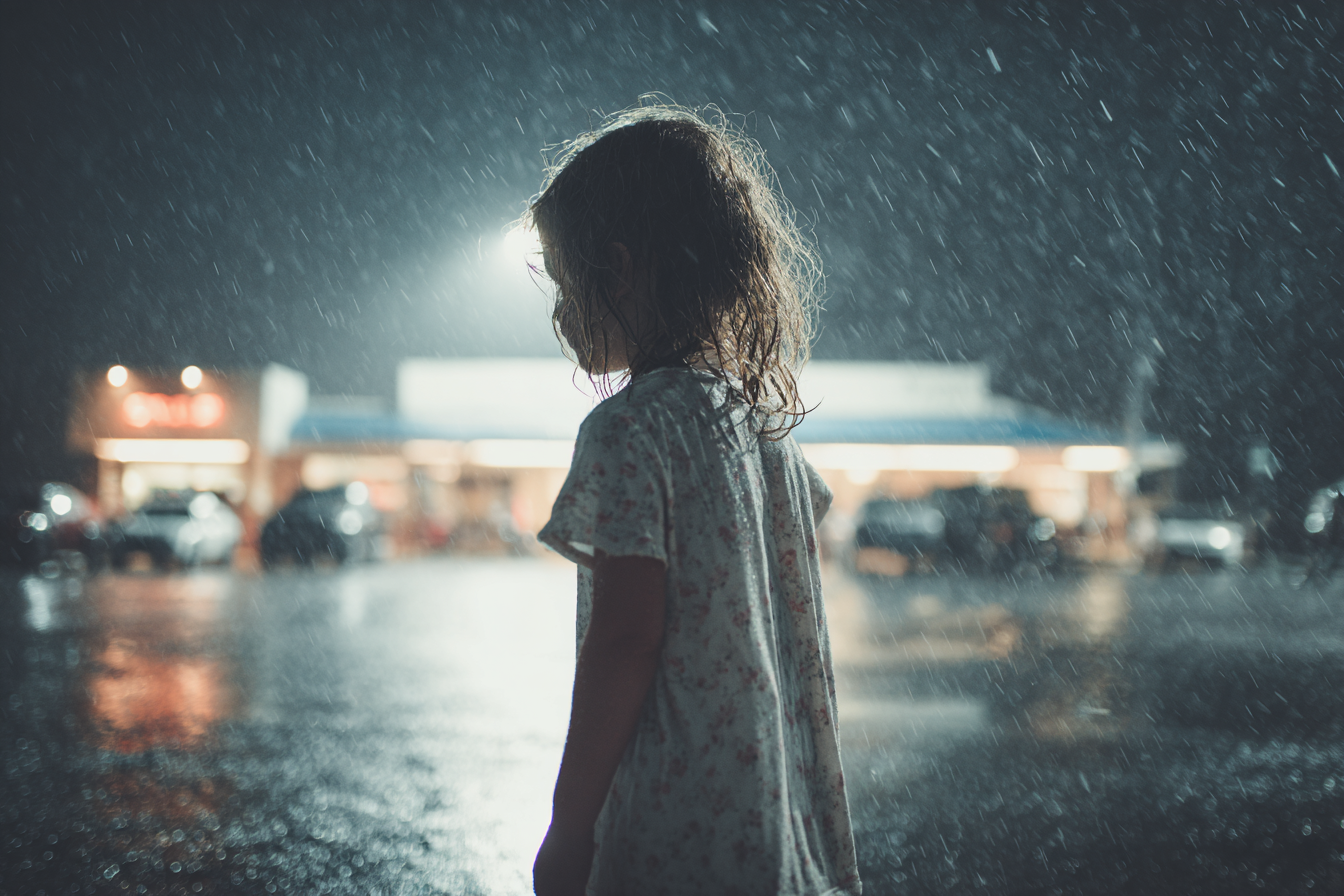 Une petite fille debout sous la pluie | Source : Midjourney
