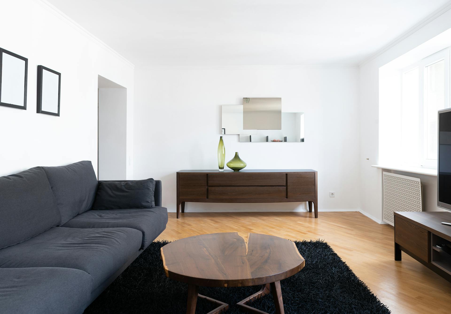 Un salon épuré avec un canapé noir, une table basse en bois et une armoire marron | Source : Pexels