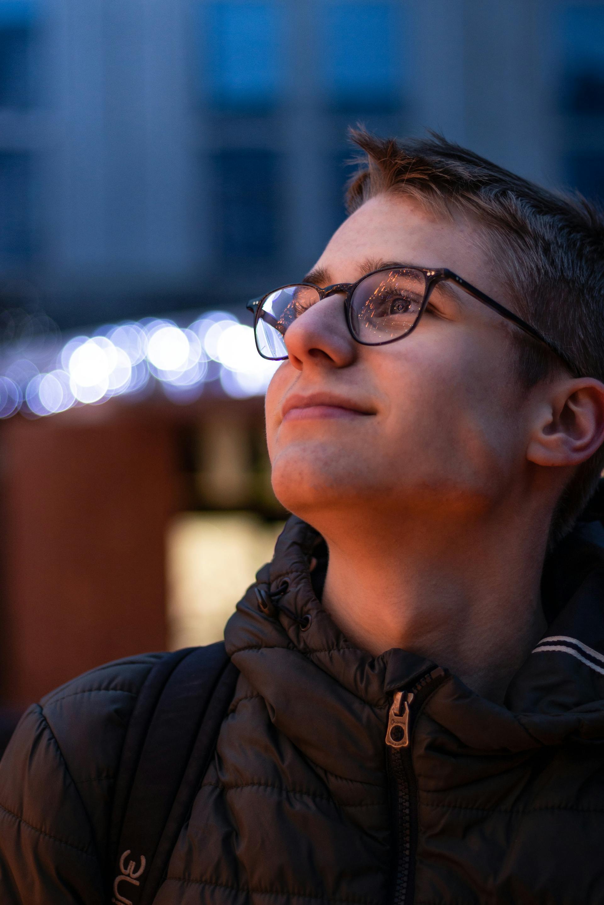 Un adolescent souriant portant une veste et des lunettes | Source : Pexels