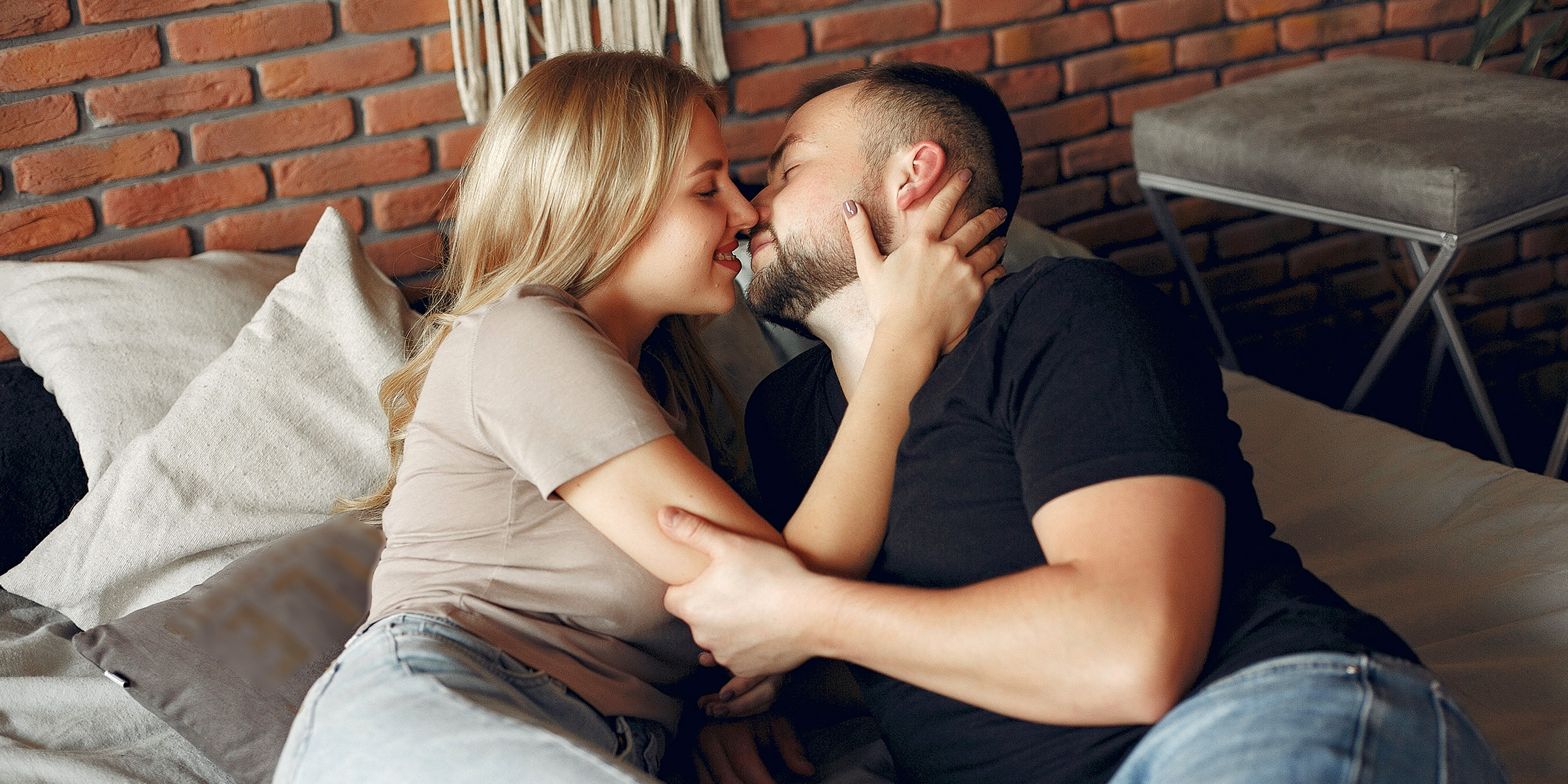 Un couple romantique allongé sur le canapé et se tenant l'un l'autre | Source : Freepik