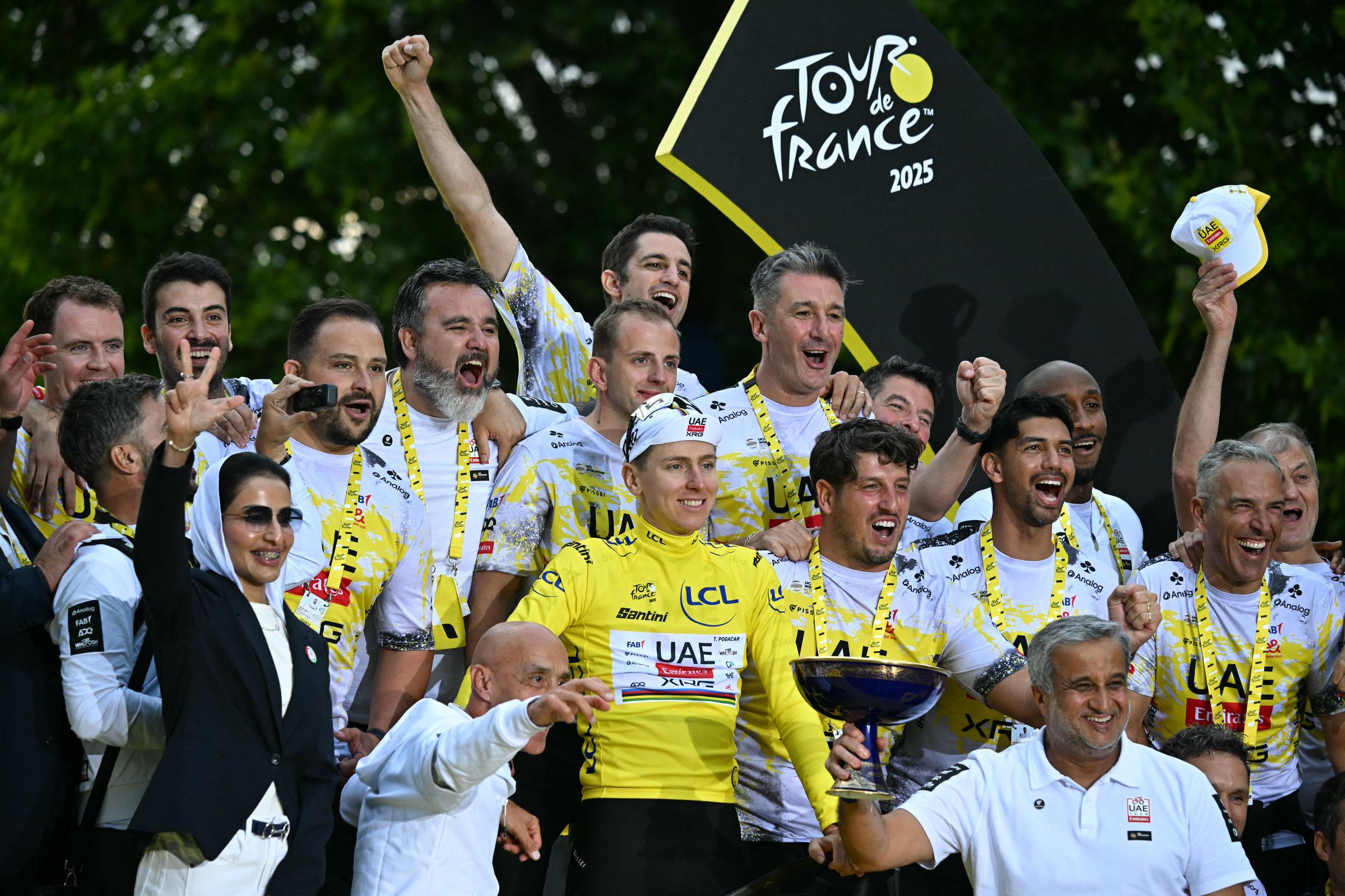 Le coureur slovène Tadej Pogacar, de l'équipe UAE Team Emirates - XRG, vêtu du maillot jaune de leader du classement général, célèbre avec le personnel de son équipe sur le podium après la 21e et dernière étape de la 112e édition du Tour de France, une course cycliste de 132,3 km entre Mantes-la-Ville et les Champs-Élysées, à Paris, le 27 juillet 2025 I Source : Getty Images