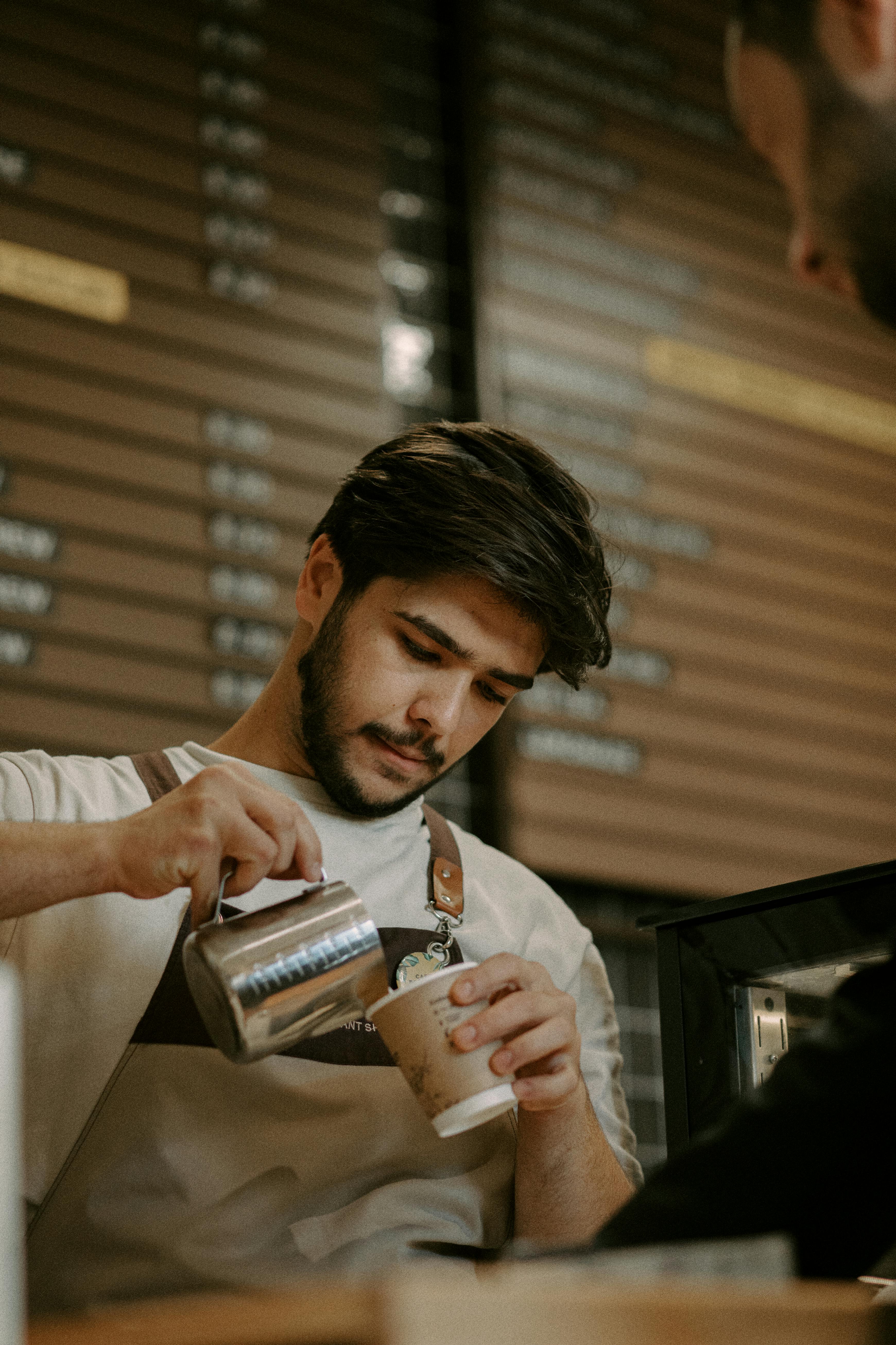 Barista versant du lait dans du café | Source : Pexels