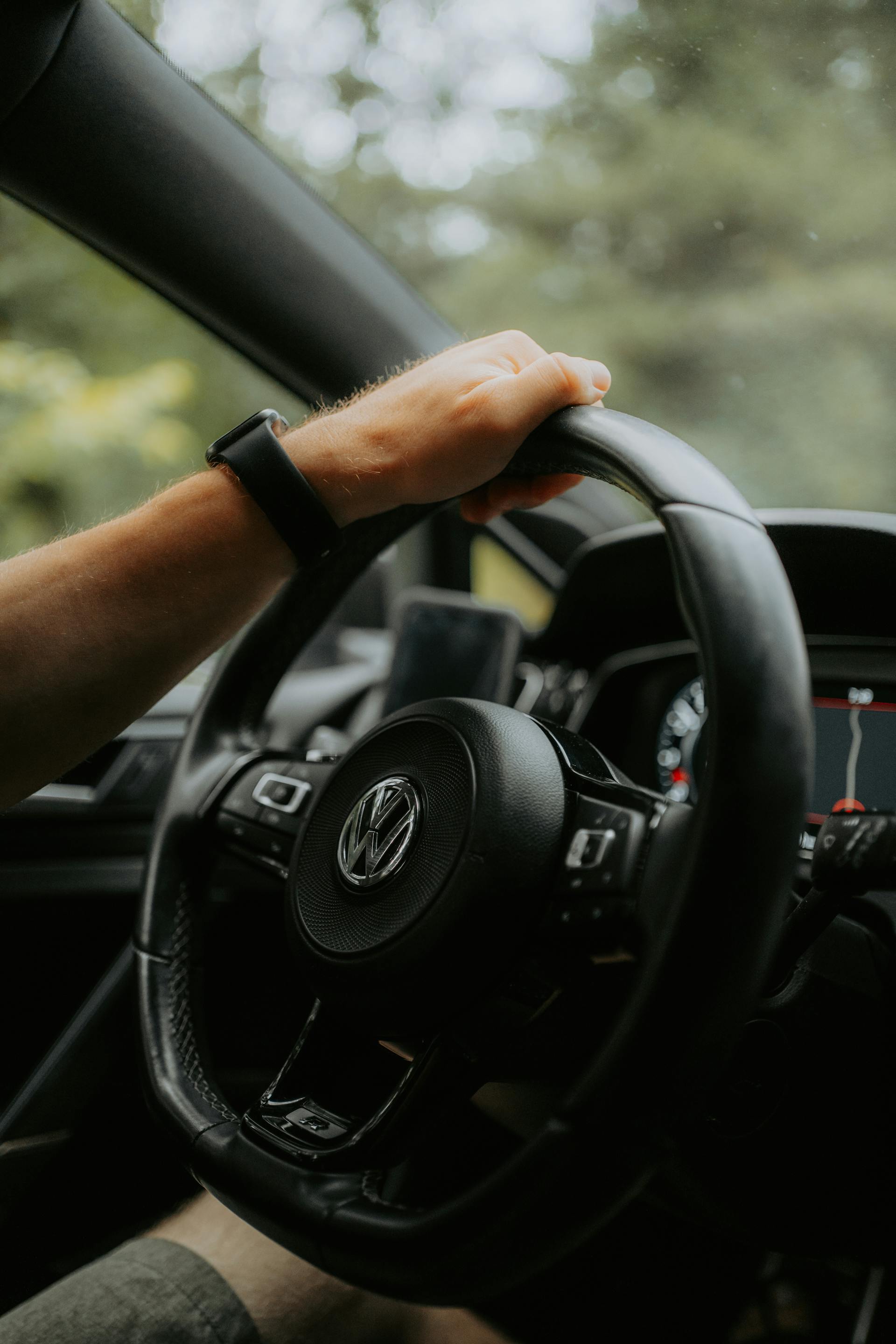 Un homme tenant le volant d'une voiture Volkswagen d'une seule main | Source : Pexels